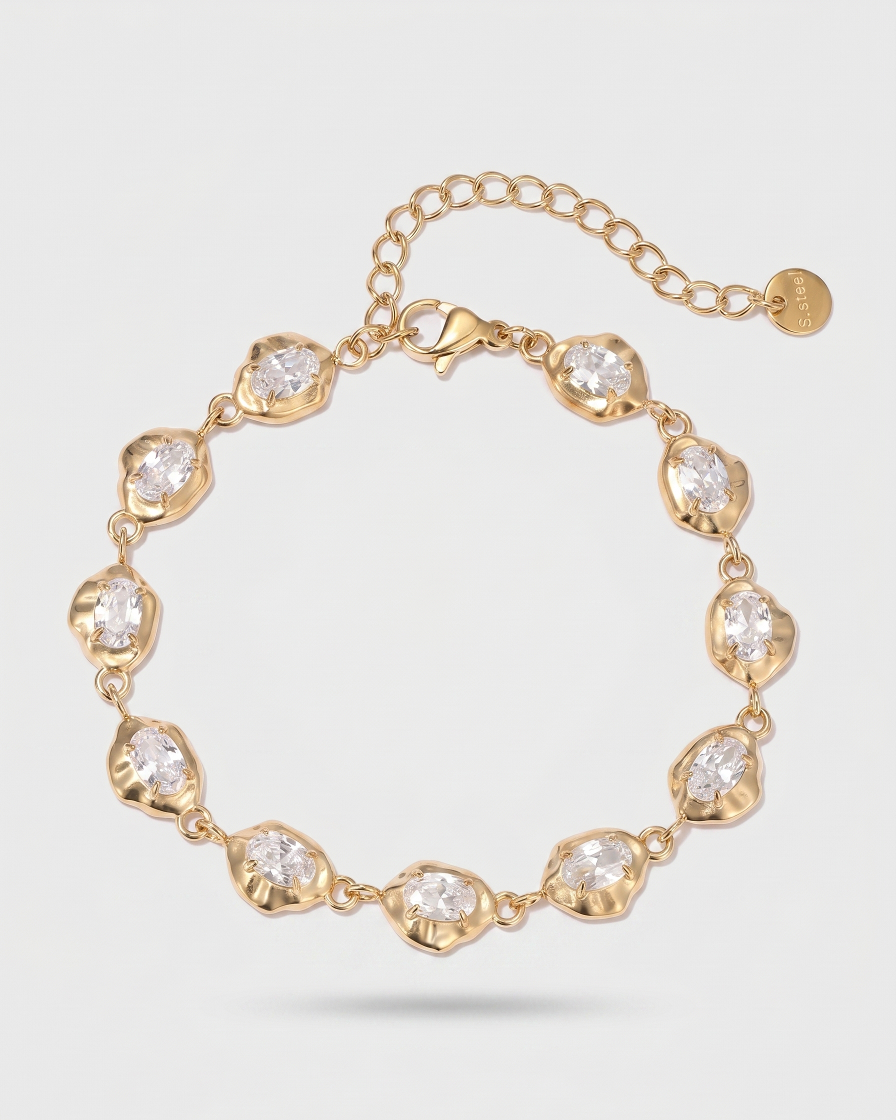 Gold bracelet with clear stones on a light gray background