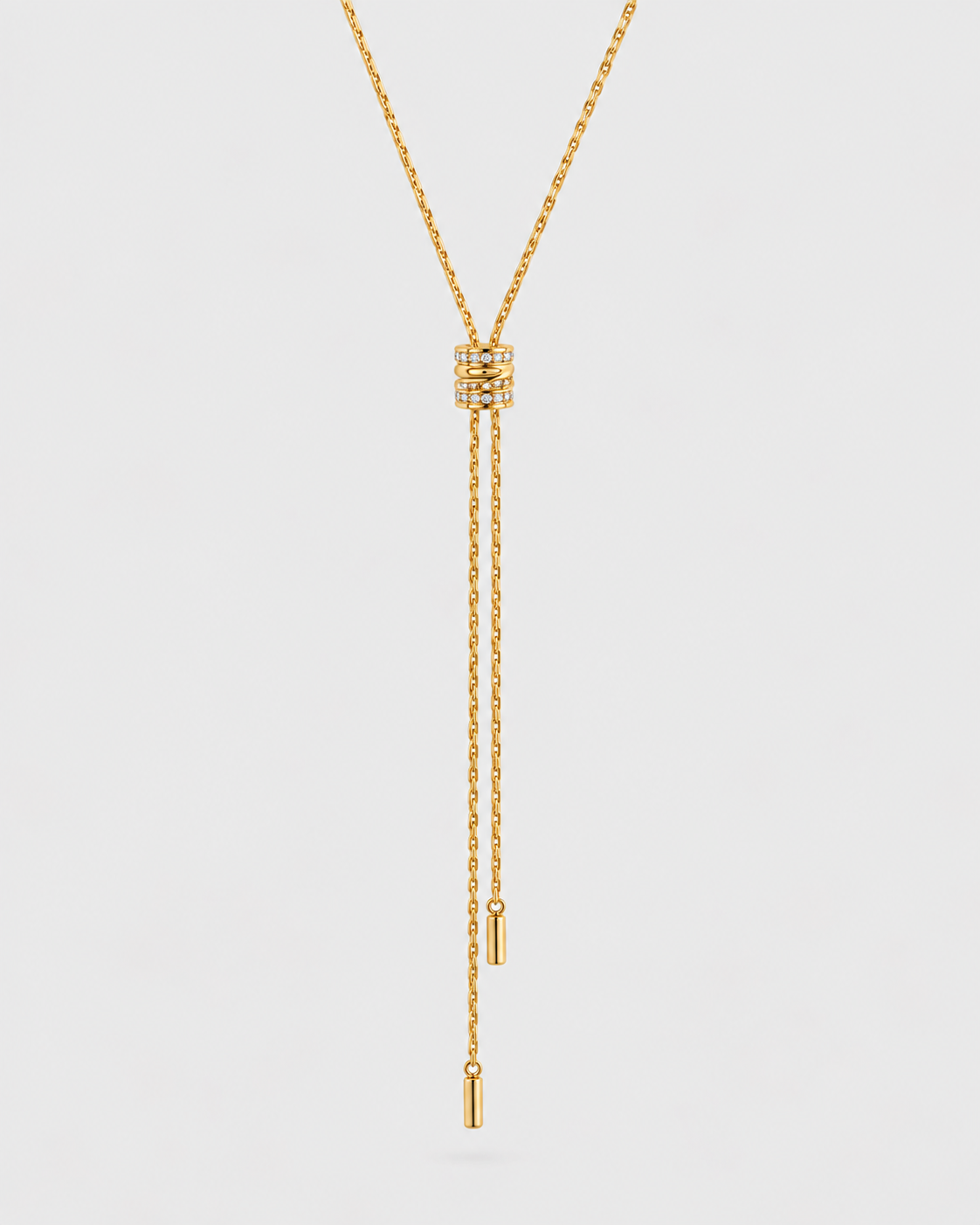 A gold Y-necklace with a textured geometric pendant and two dangling chain ends, shown on a light gray background.