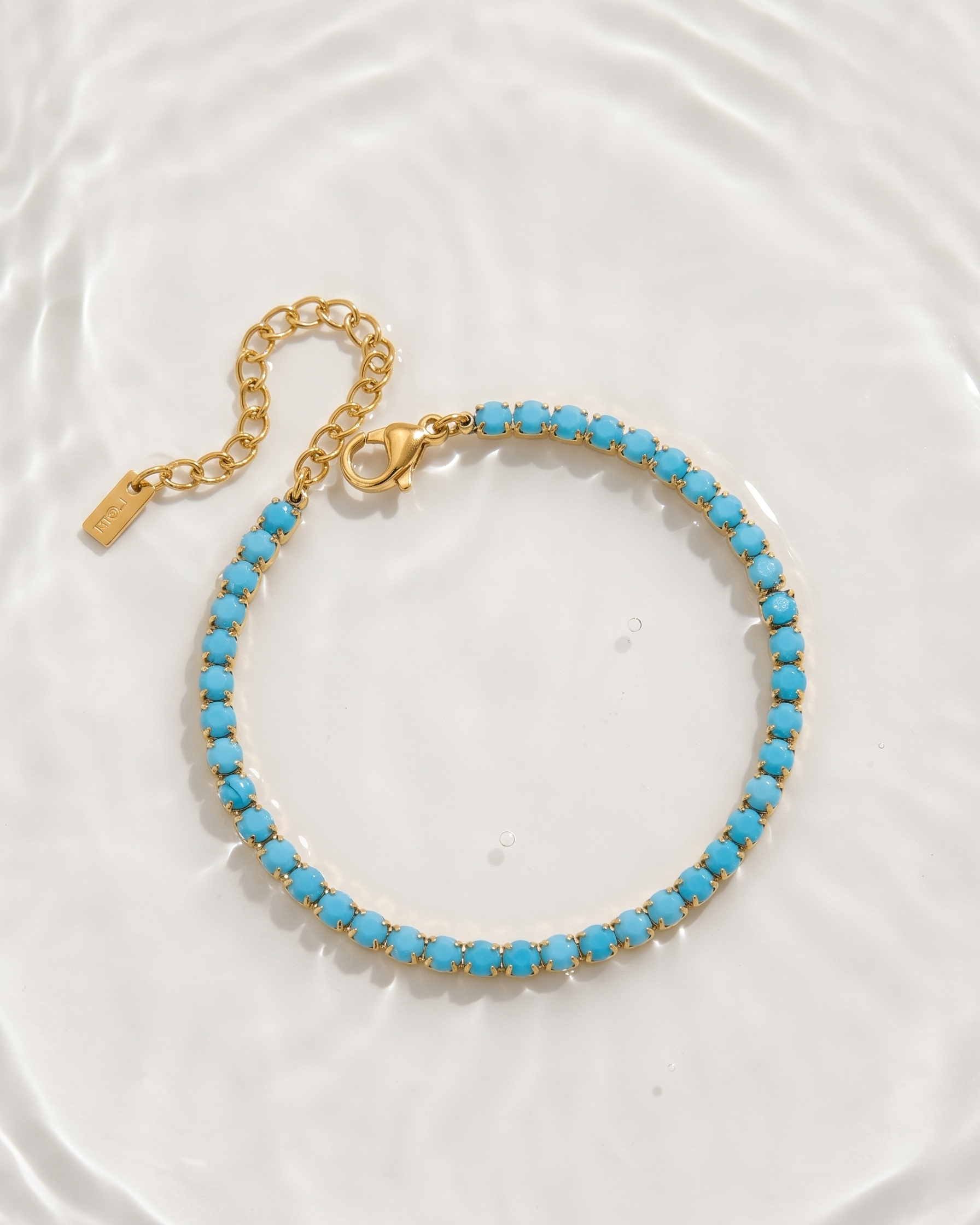 Turquoise beaded bracelet with gold chain on a white background