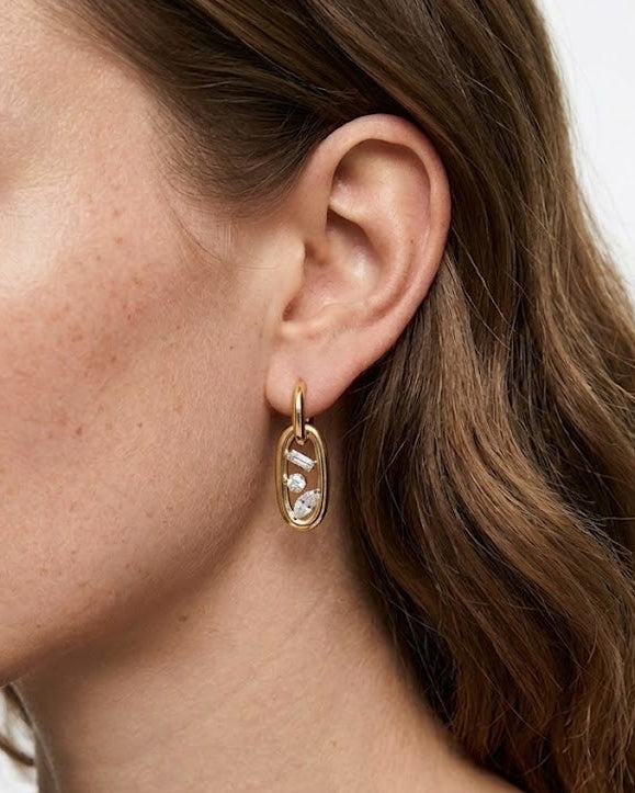 Close-up of a woman wearing gold hoop earrings with a white background