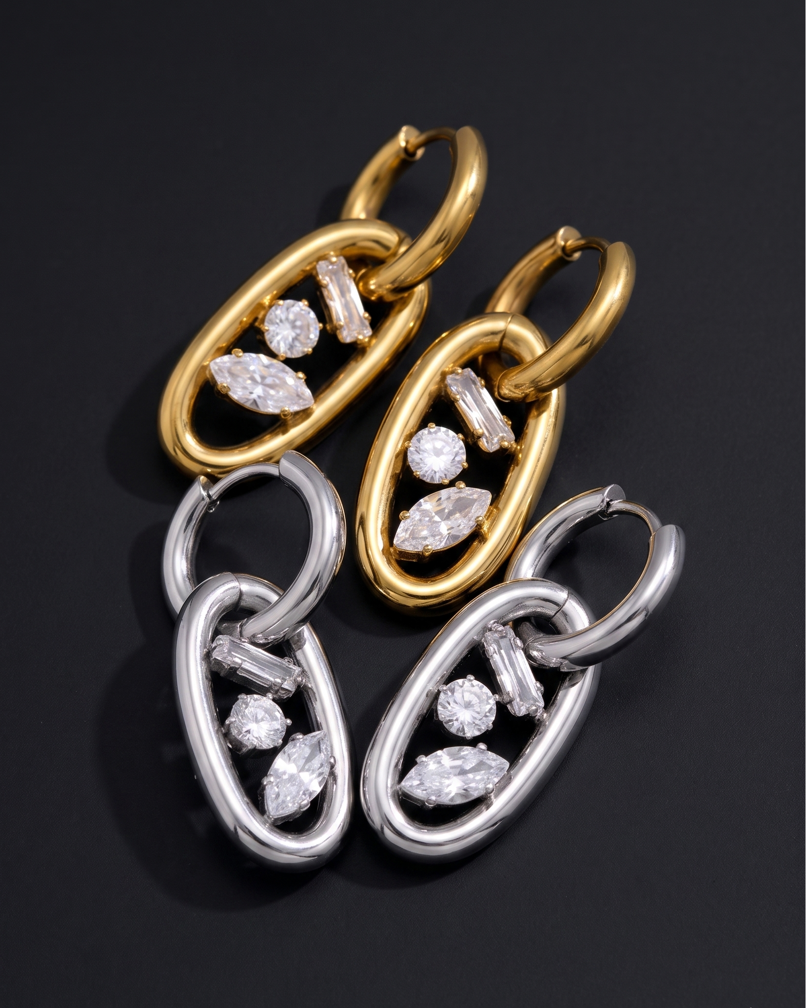 Pair of gold and silver hoop earrings with diamond-like stones on a black background
