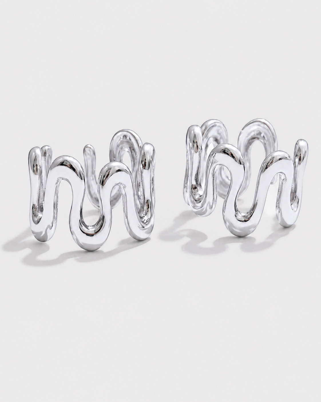 A pair of silver-toned wavy cufflinks with a polished metallic finish, displayed on a clean light gray background.