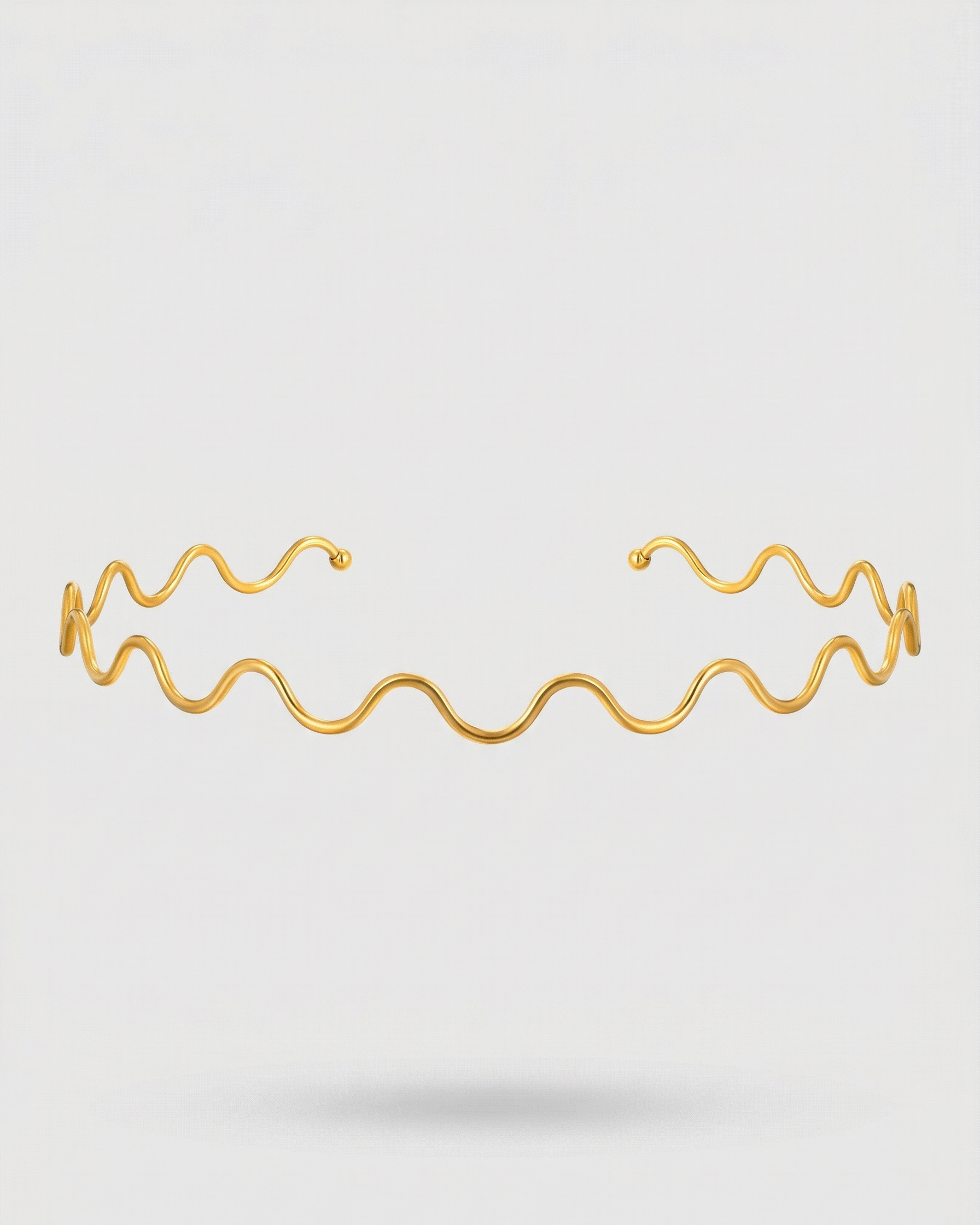 Gold bracelet with wavy design on a light gray background