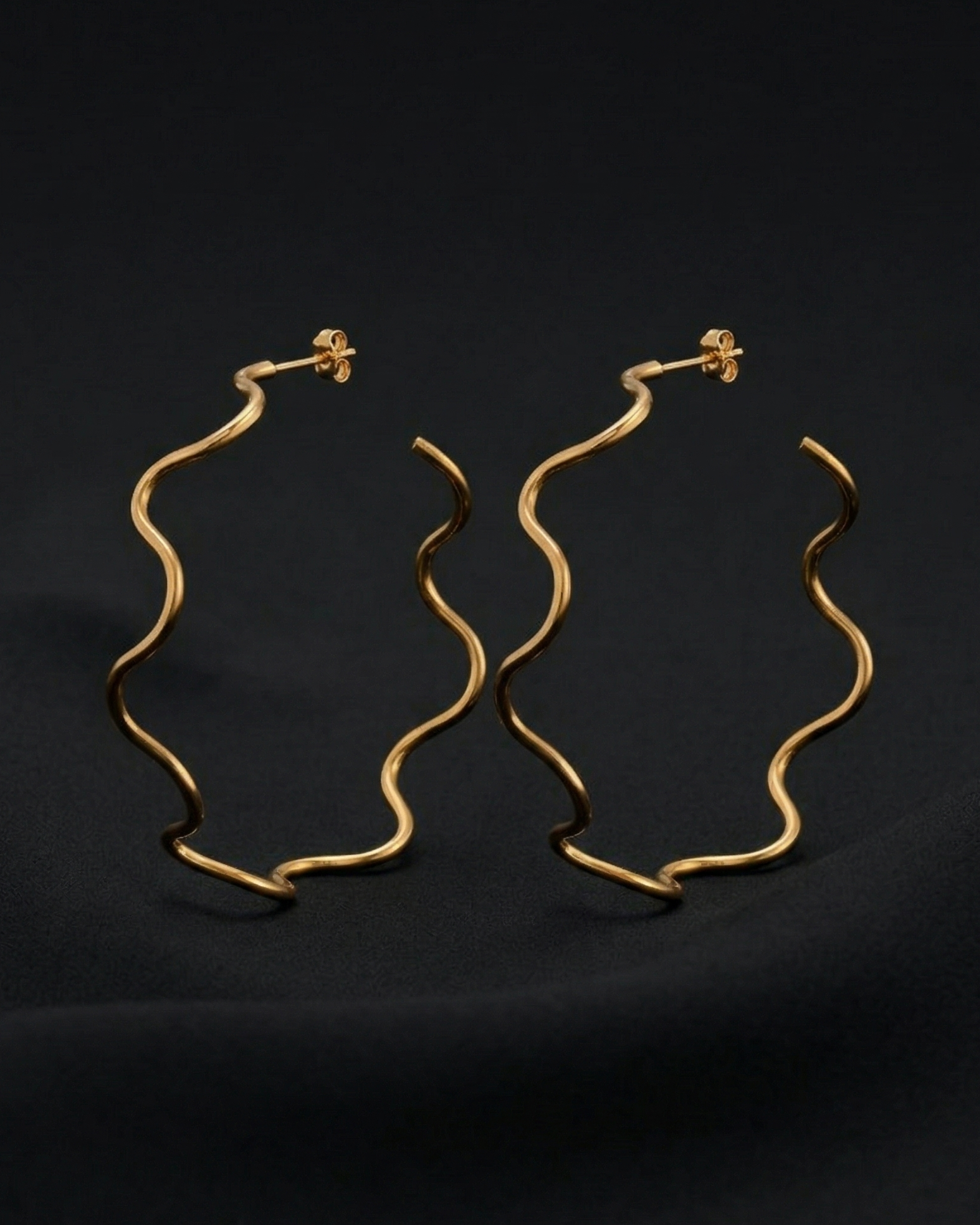 Gold hoop earrings on a black background