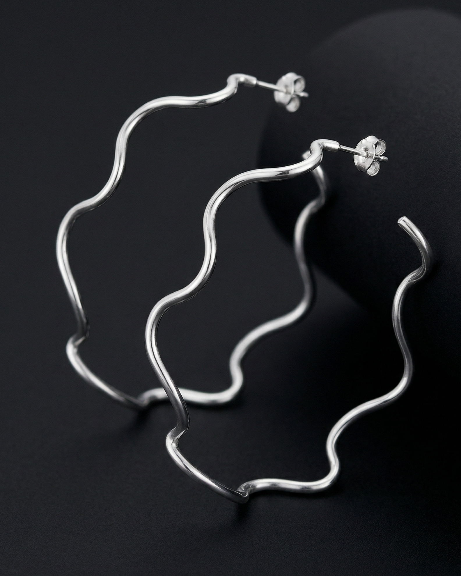 Silver earrings on a black background