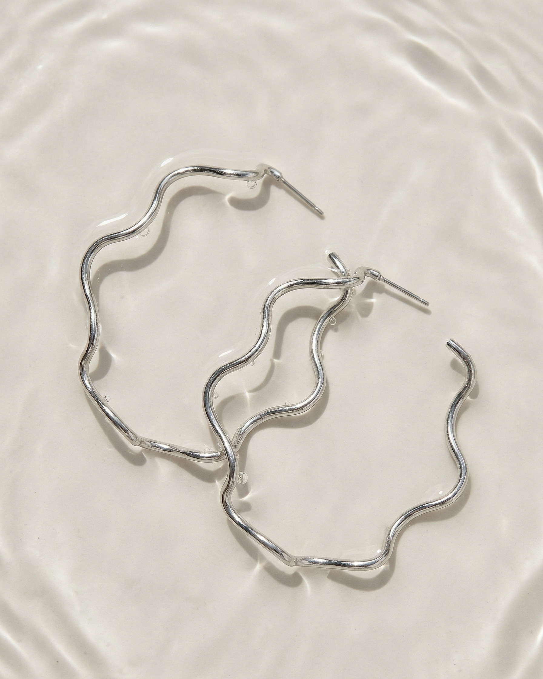 Silver hoop earrings on a light beige surface
