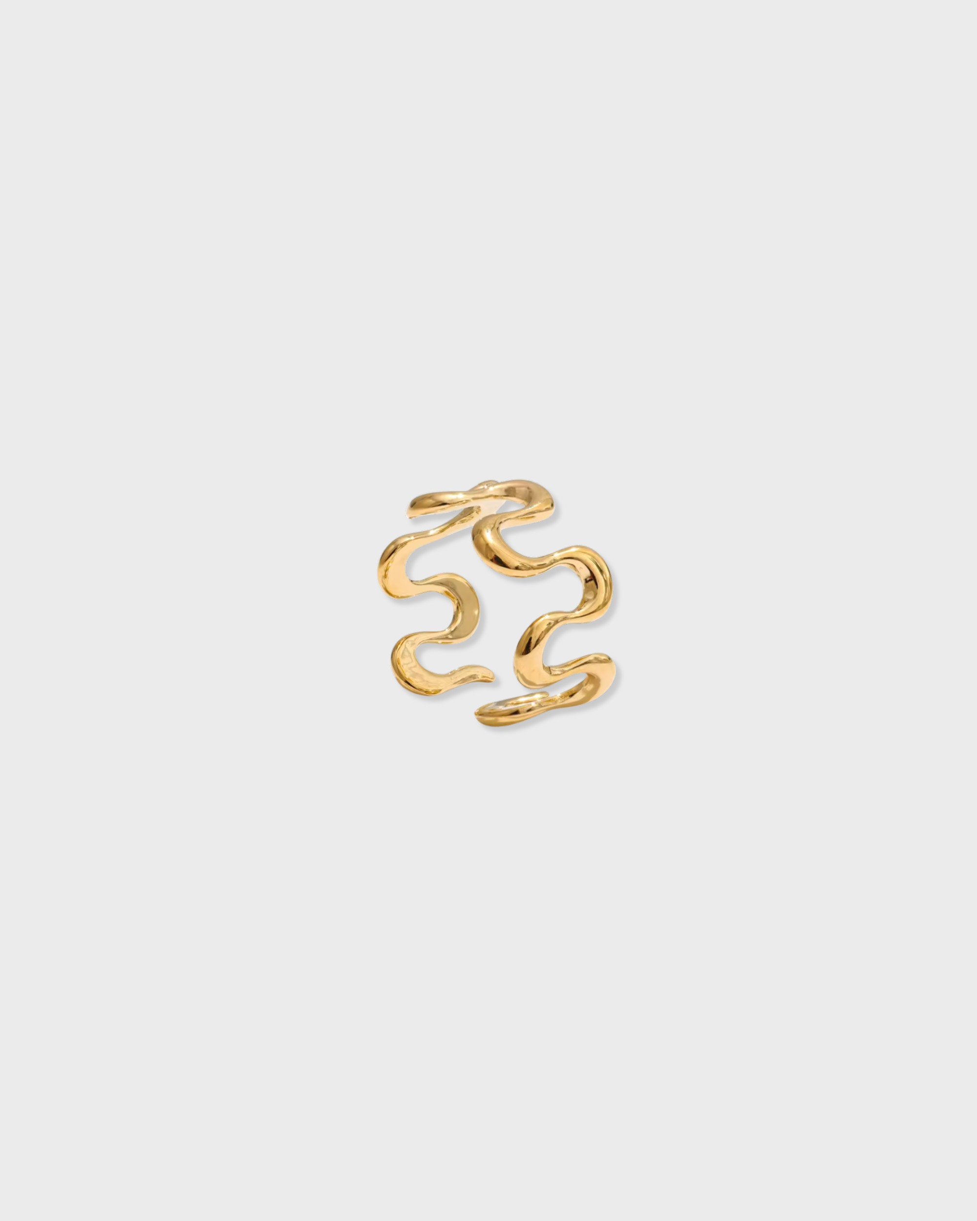 Gold ring with wavy design on a light gray background
