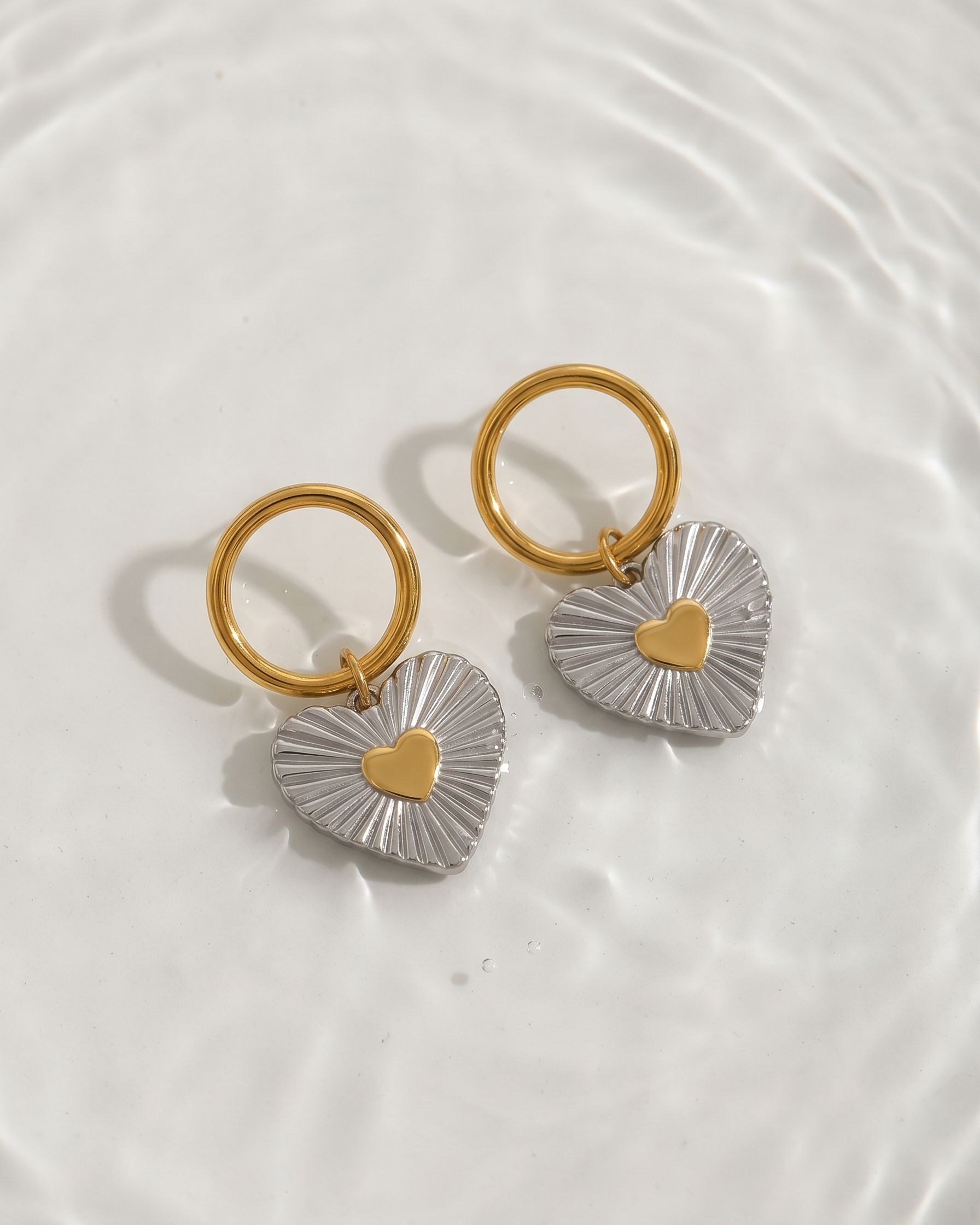 Pair of gold and silver heart-shaped earrings on a white background