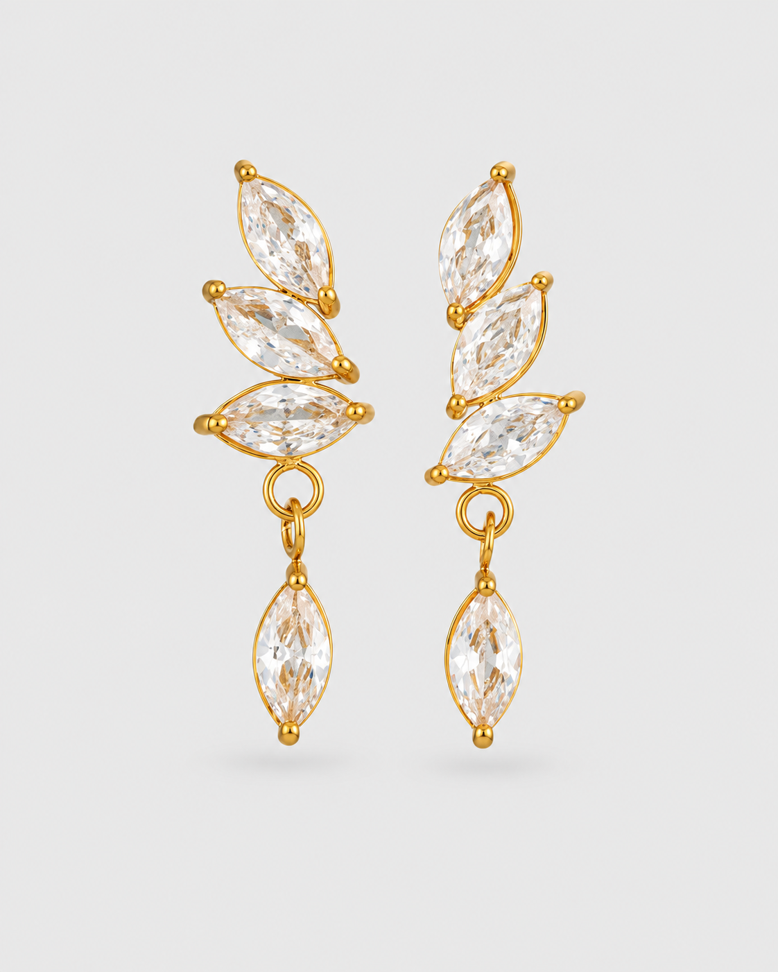 A pair of gold drop earrings featuring marquise-cut clear crystals arranged in a leaf-like cluster with a dangling marquise crystal at the bottom, shown on a light gray background.