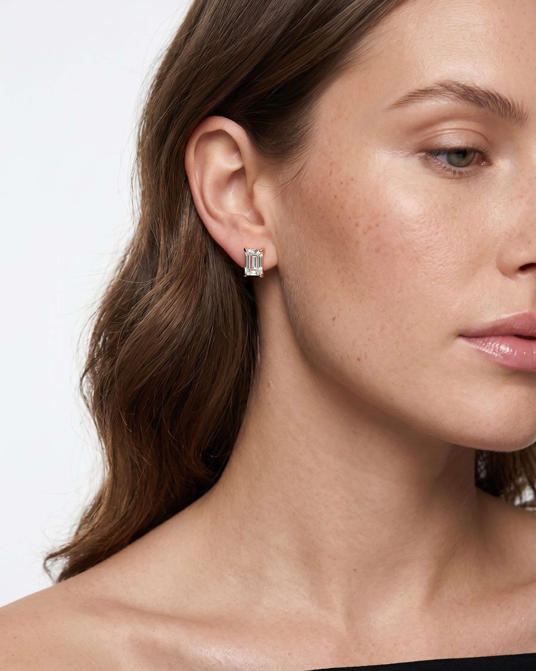 Close-up of a woman wearing a diamond earring on a plain background