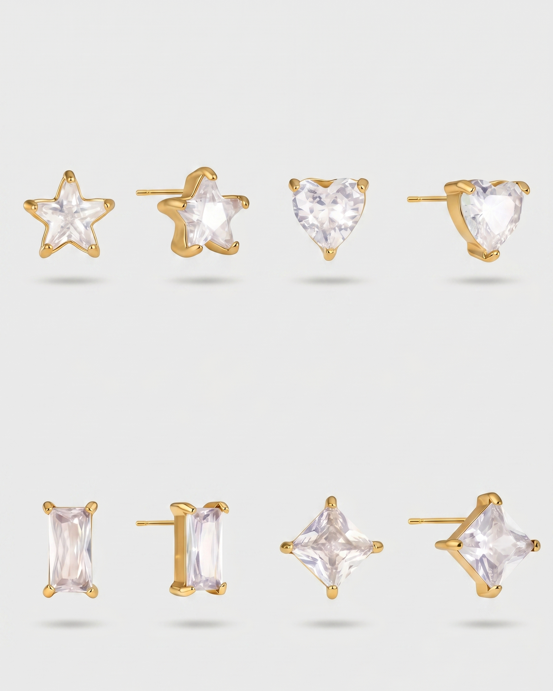 Set of gold and clear gemstone earrings on a light gray background