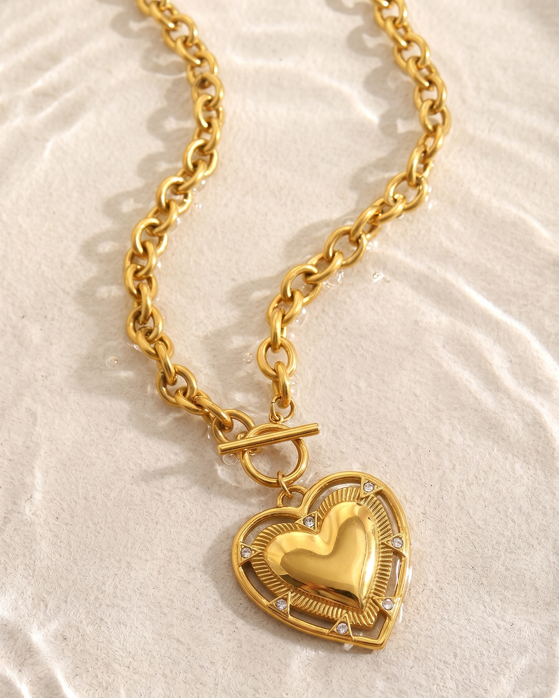 Gold heart-shaped pendant necklace on a textured beige background