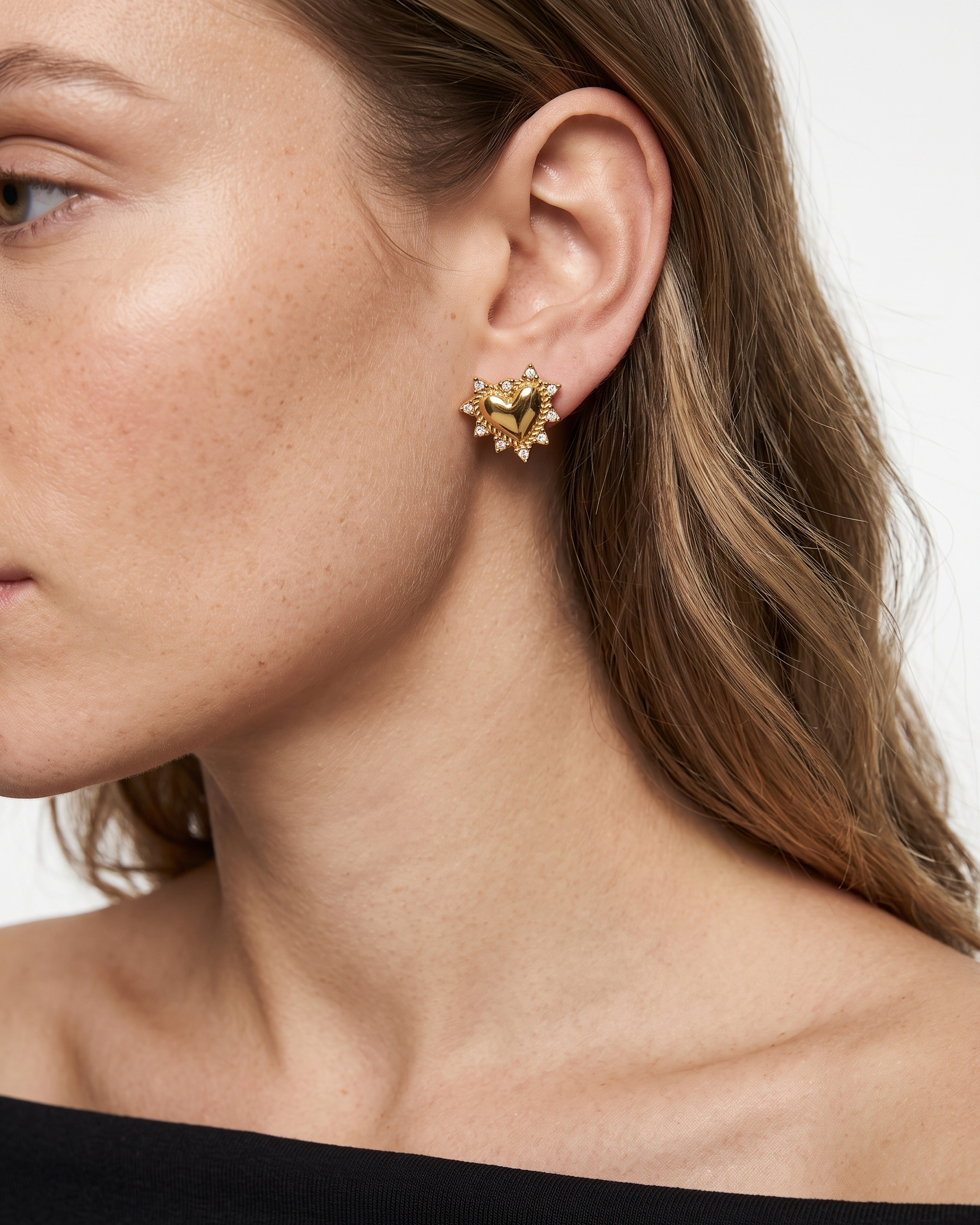 Close-up of a woman wearing gold heart-shaped earrings with a blurred background