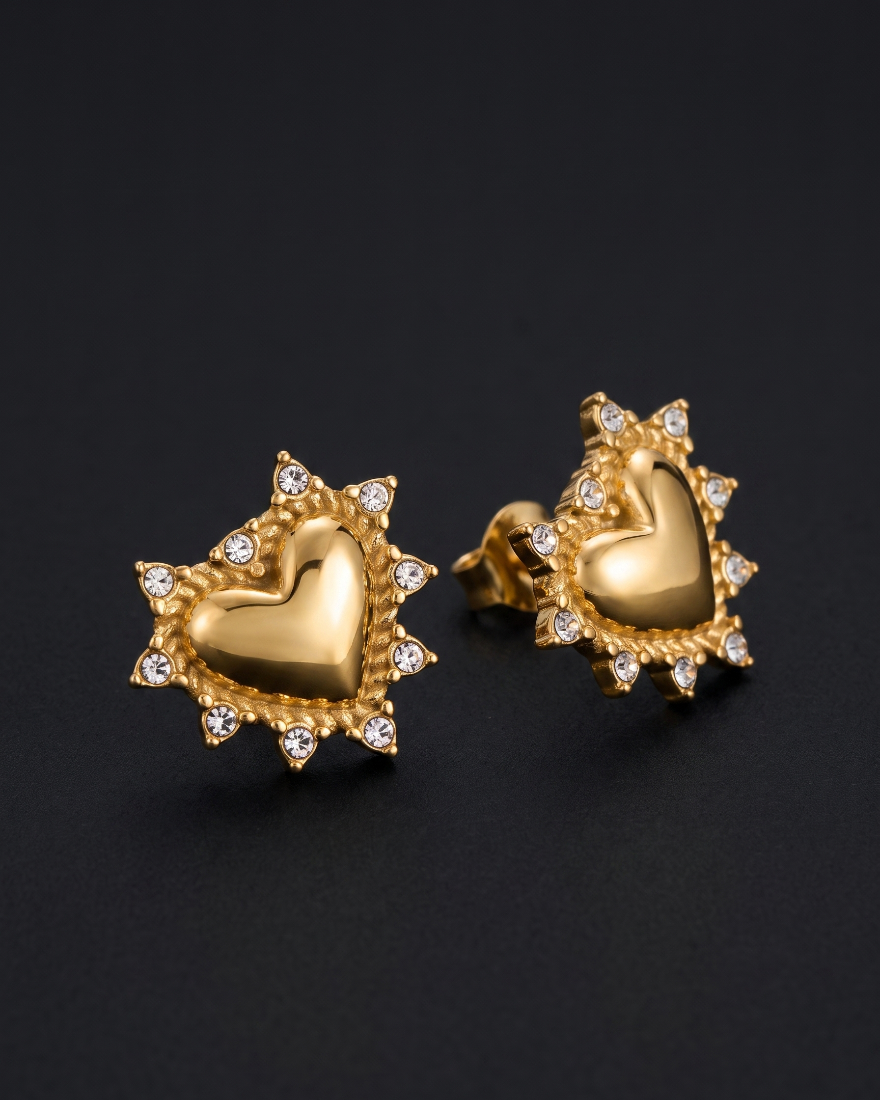 Gold heart-shaped earrings with diamond accents on a black background