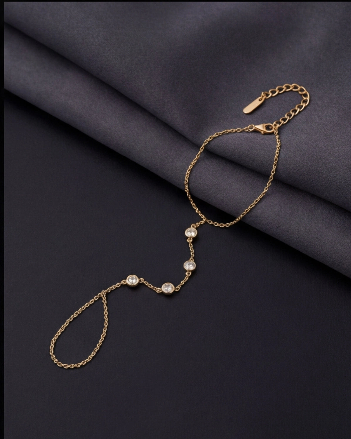Gold bracelet with pearl-like beads on a dark fabric background