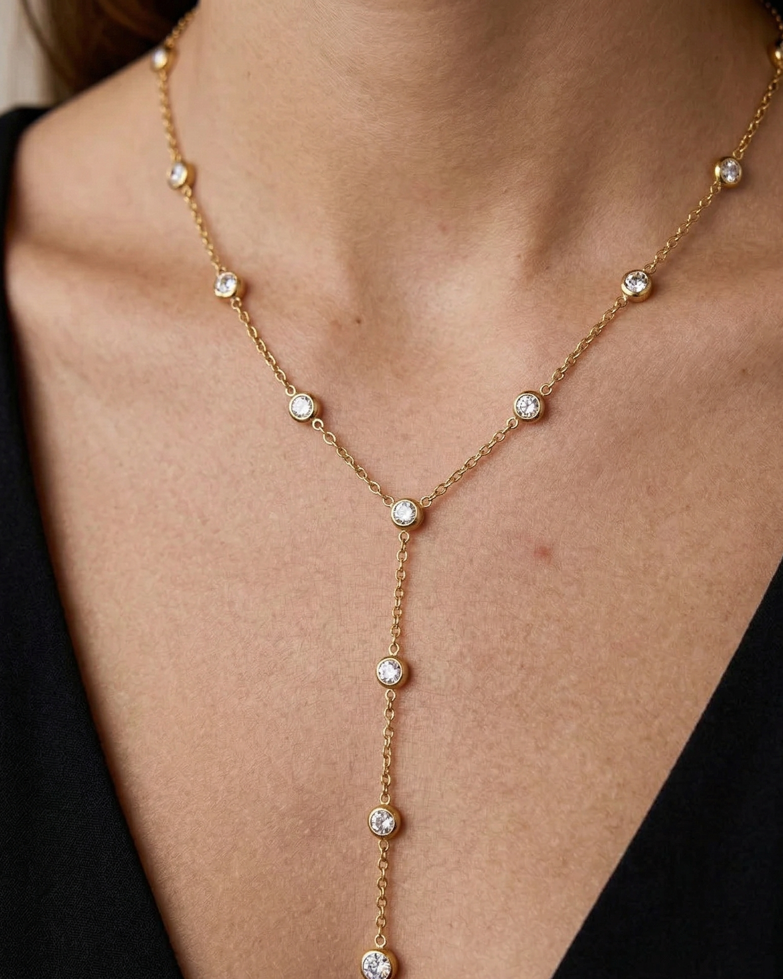 Gold necklace with small diamonds on a person wearing a black top