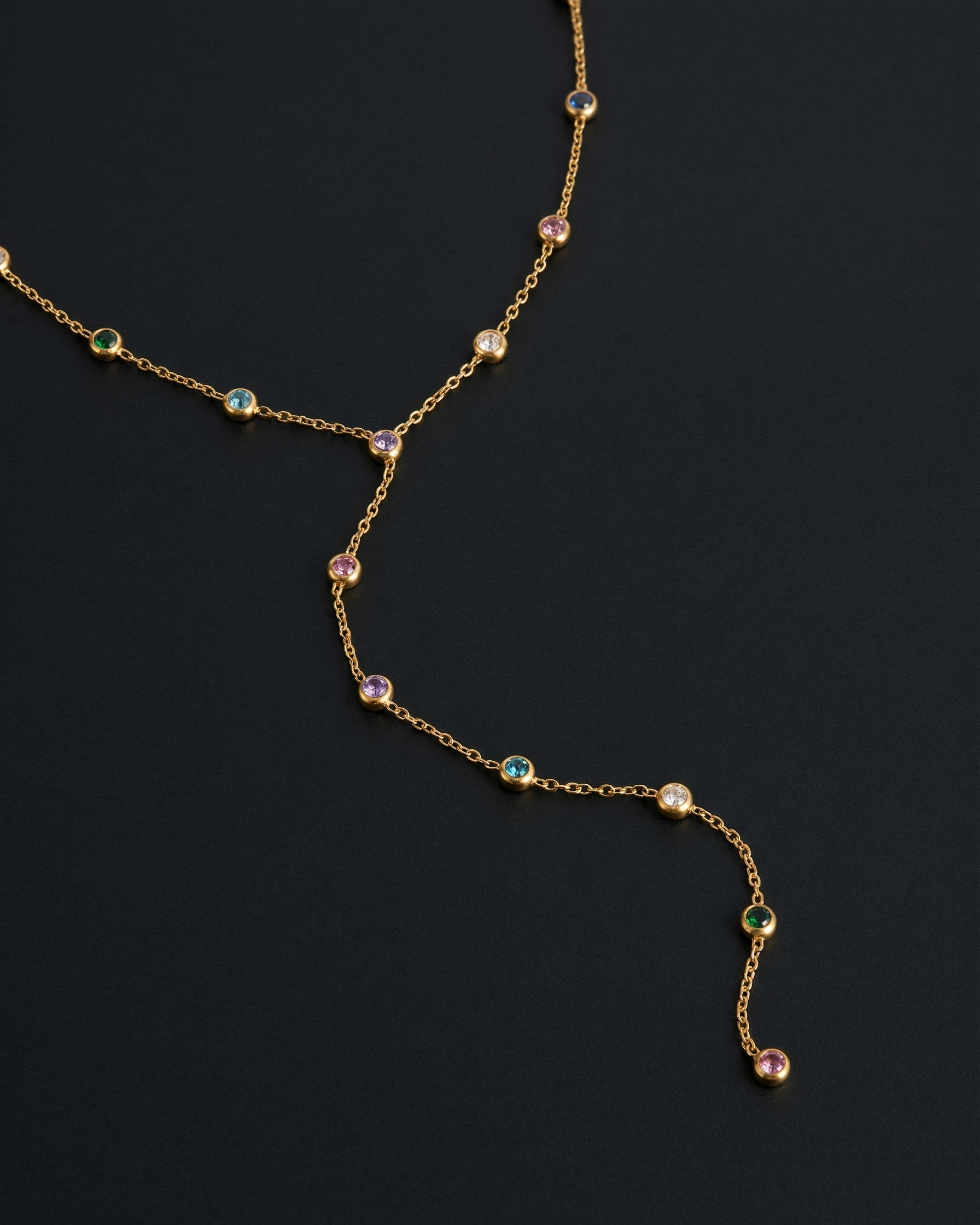 Delicate gold necklace with gemstones on a dark background