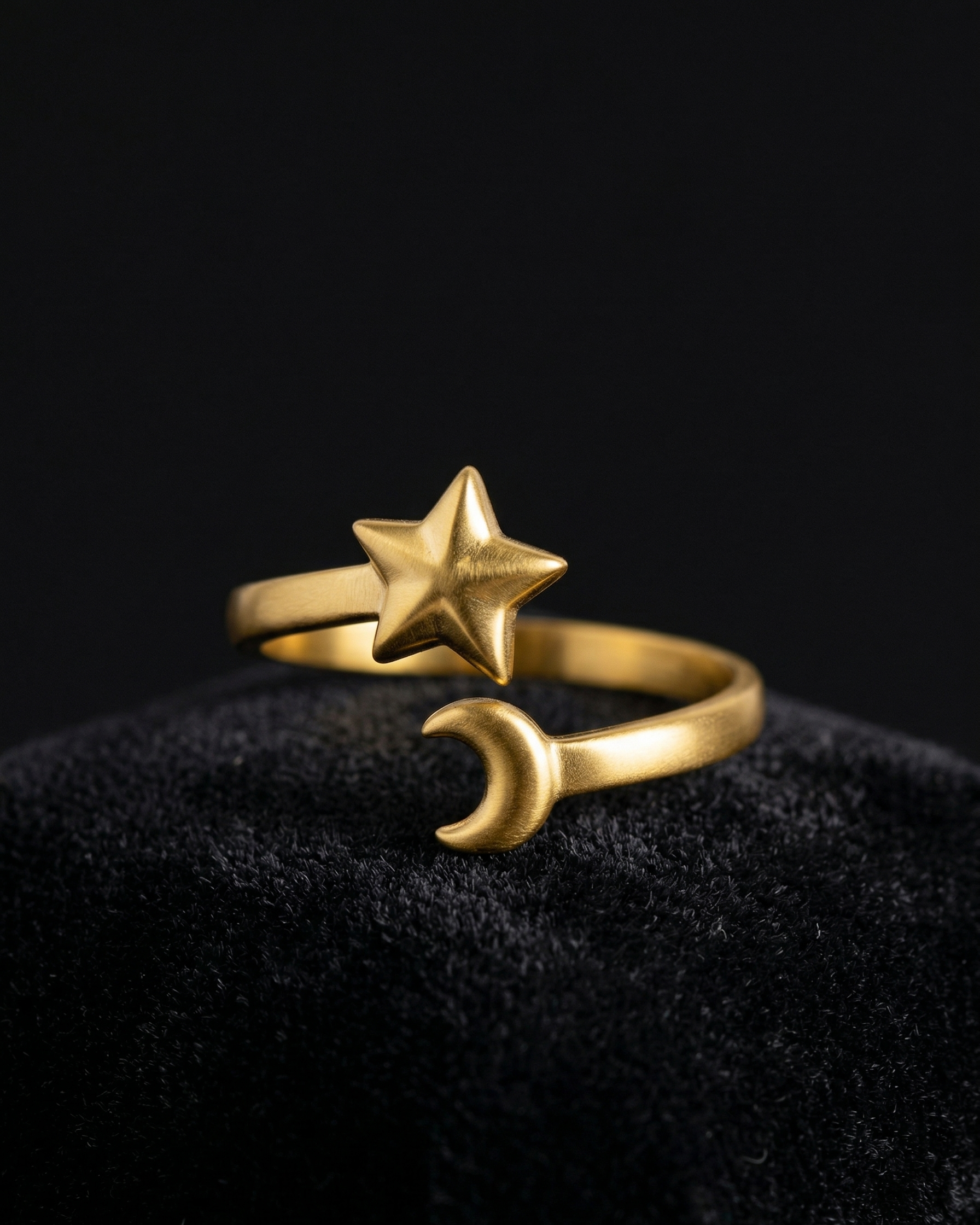 Gold ring with star and moon design on a black background
