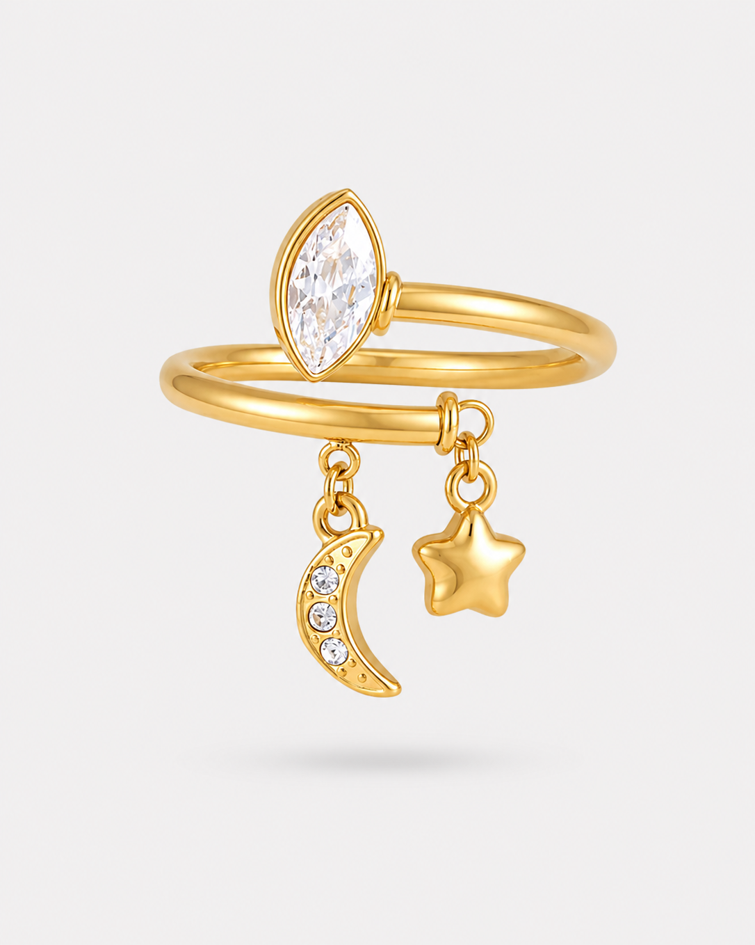 Gold-plated double-band ring featuring a marquise-cut clear gemstone, a dangling crescent moon charm with small clear stones, and a dangling star charm, shown on a light gray background.
