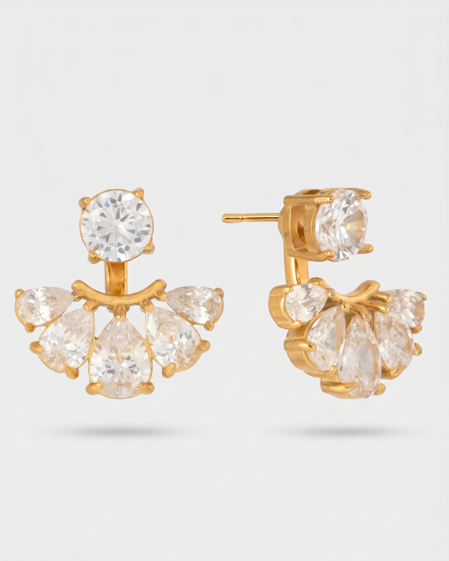 Gold earrings with clear gemstones on a light gray background