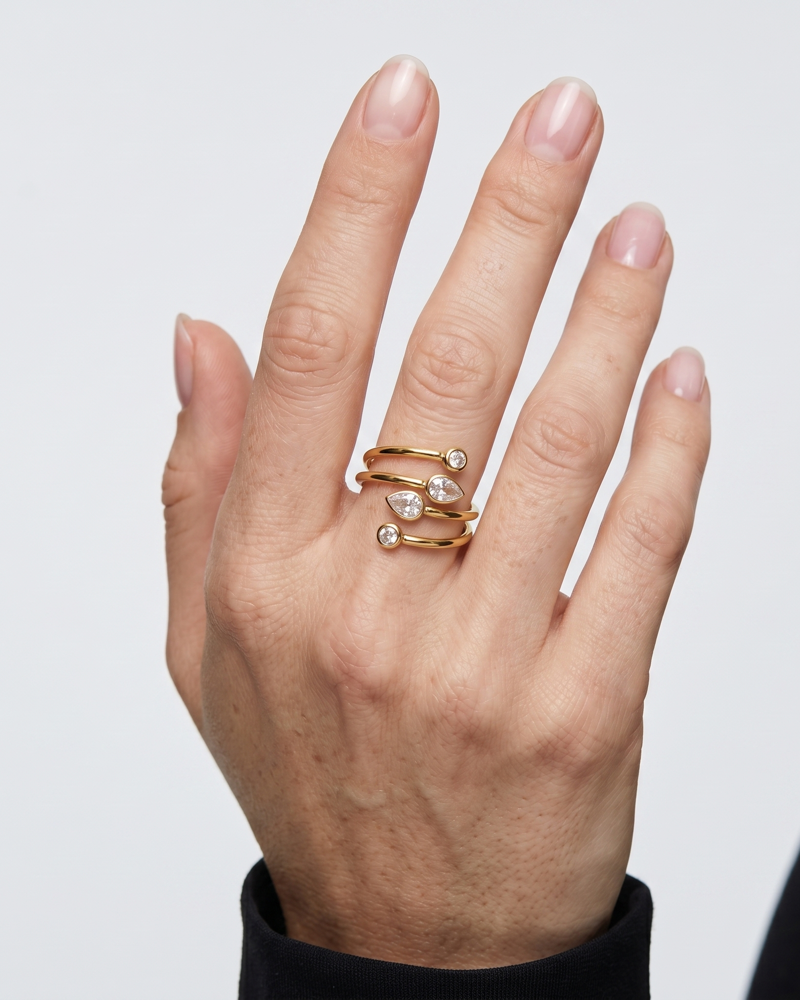 Hand wearing a gold ring with small diamonds on a light gray background
