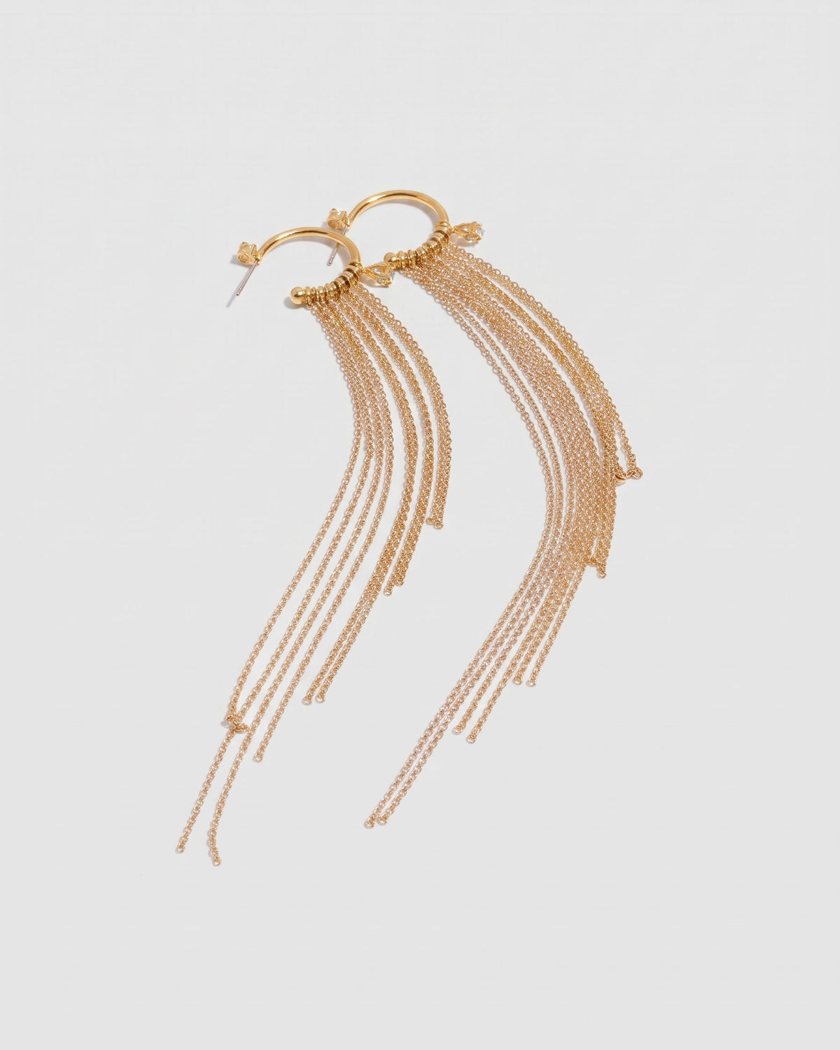 A pair of gold-toned dangle earrings with circular hoops connected by multiple thin chain strands, shown on a plain light gray background.