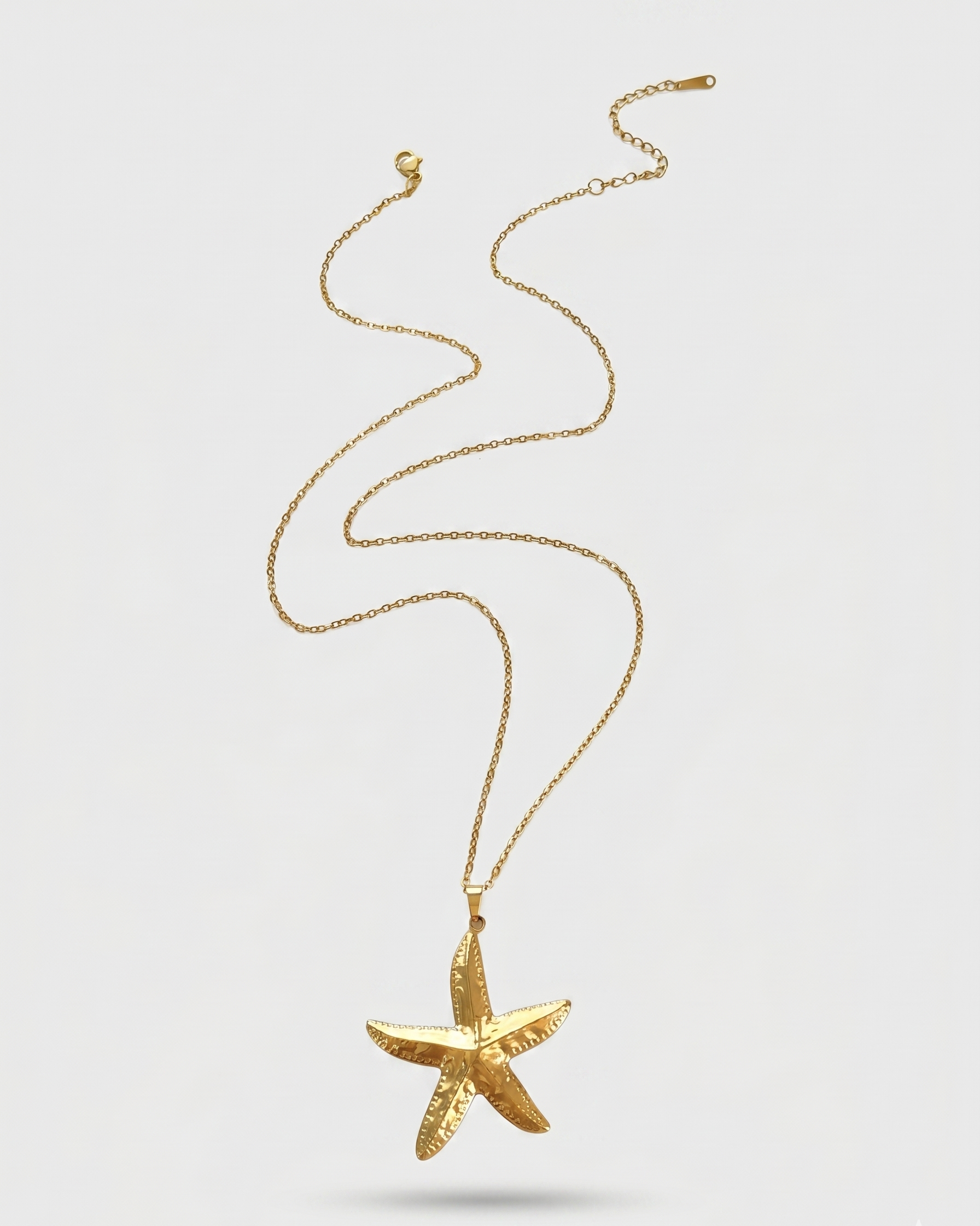 Gold starfish pendant necklace on a white background