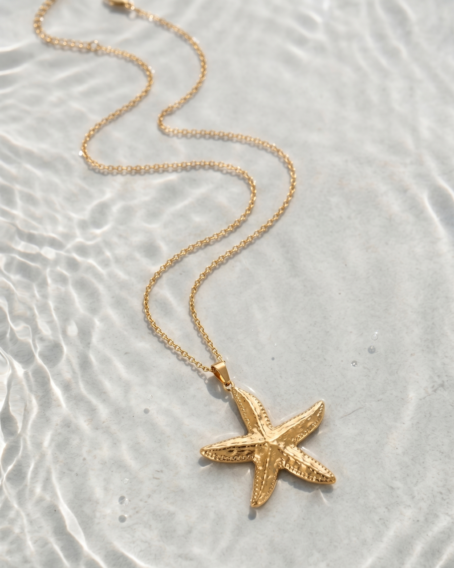 Gold starfish pendant necklace on a textured surface
