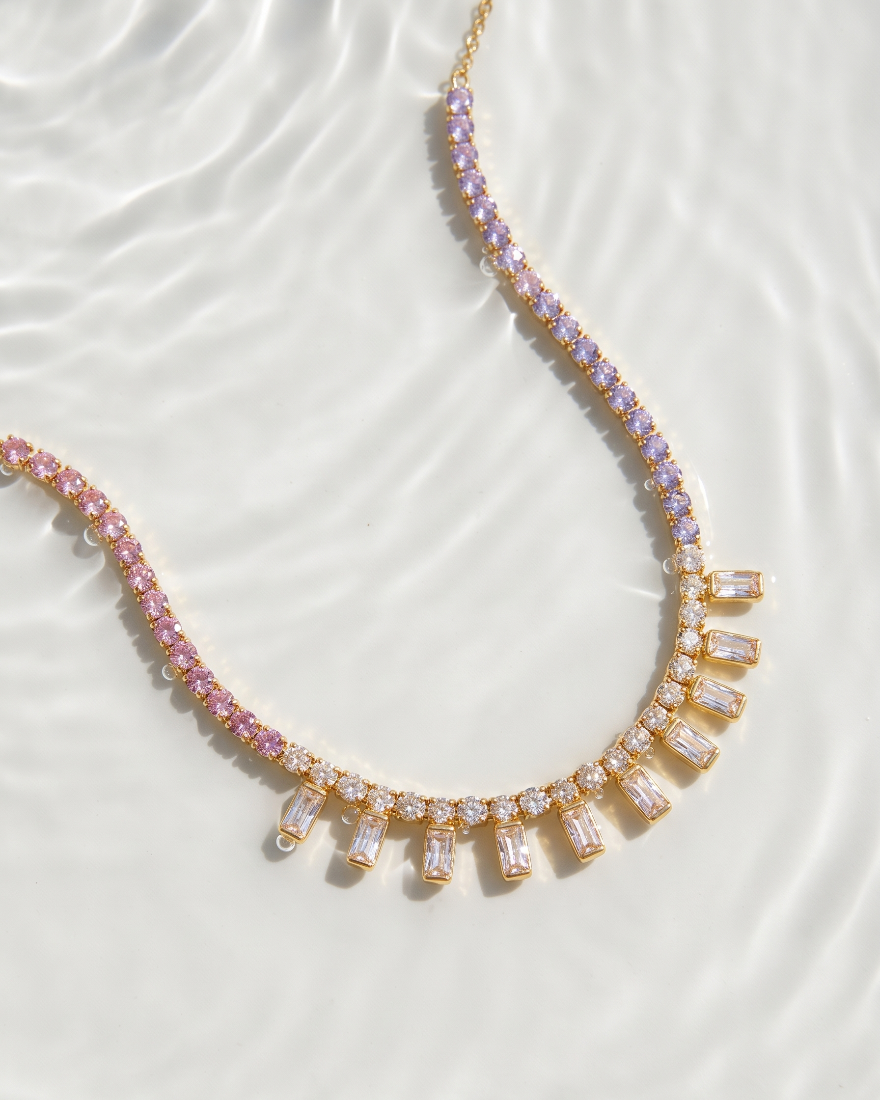 Necklace with pink and clear gemstones on a white fabric background