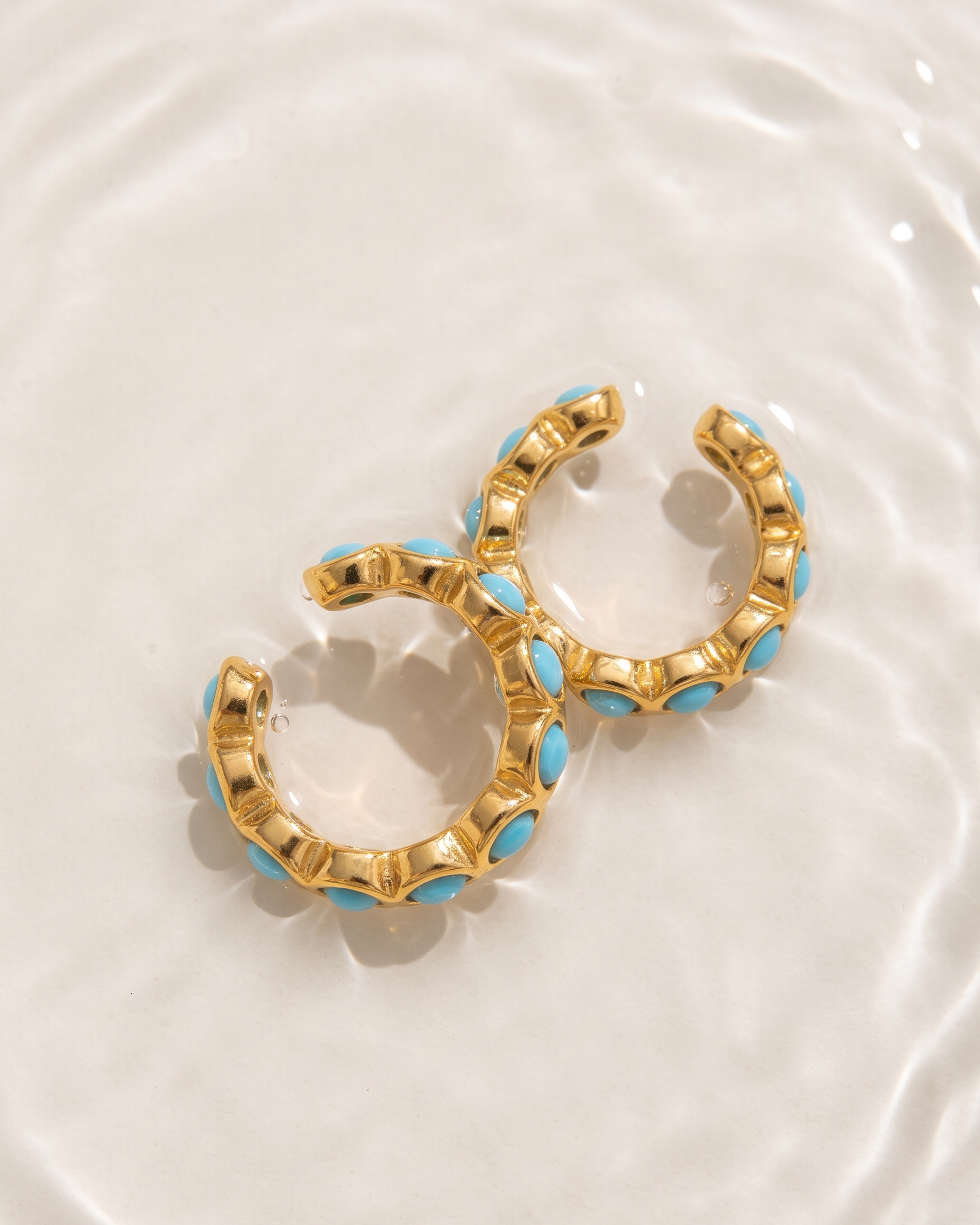 Gold hoop earrings with blue accents on a white plate