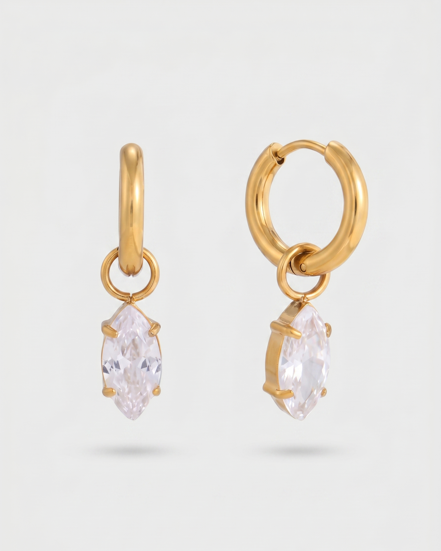 Gold hoop earrings with clear gemstones on a light gray background