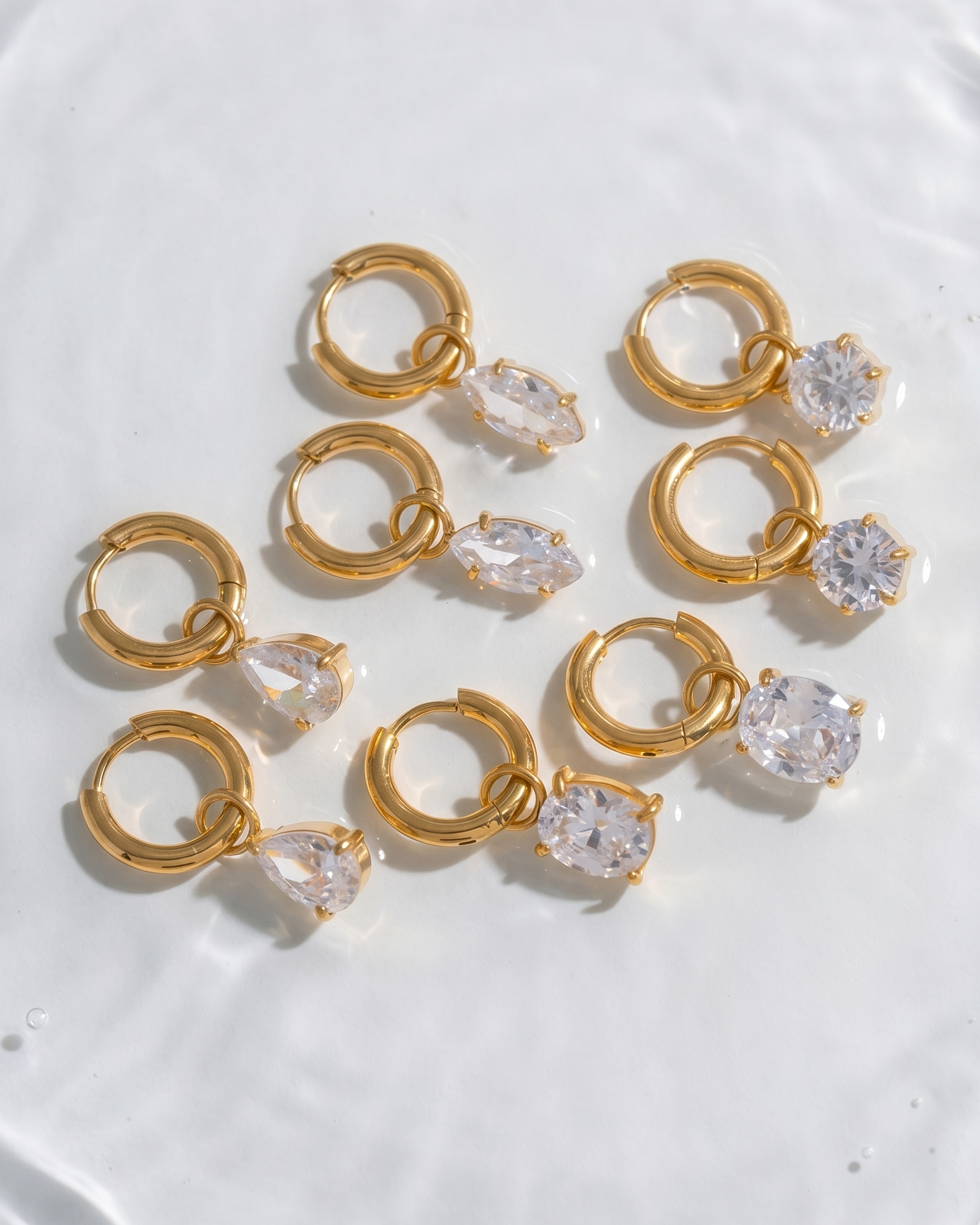 Gold hoop earrings with clear gemstones on a white surface