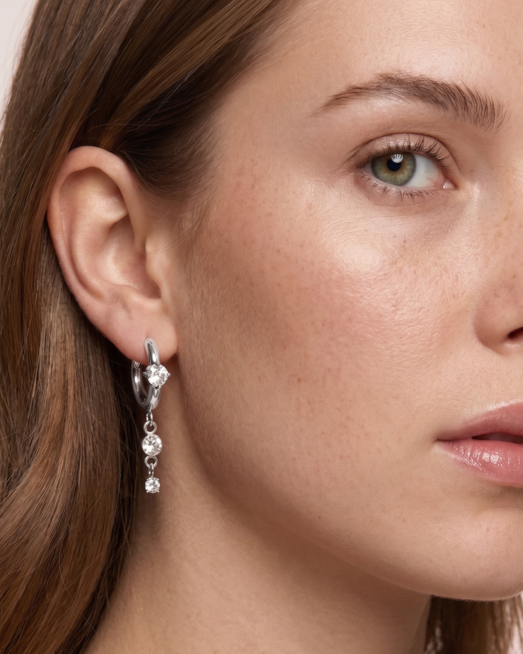 Close-up of a woman wearing diamond earrings with a neutral background