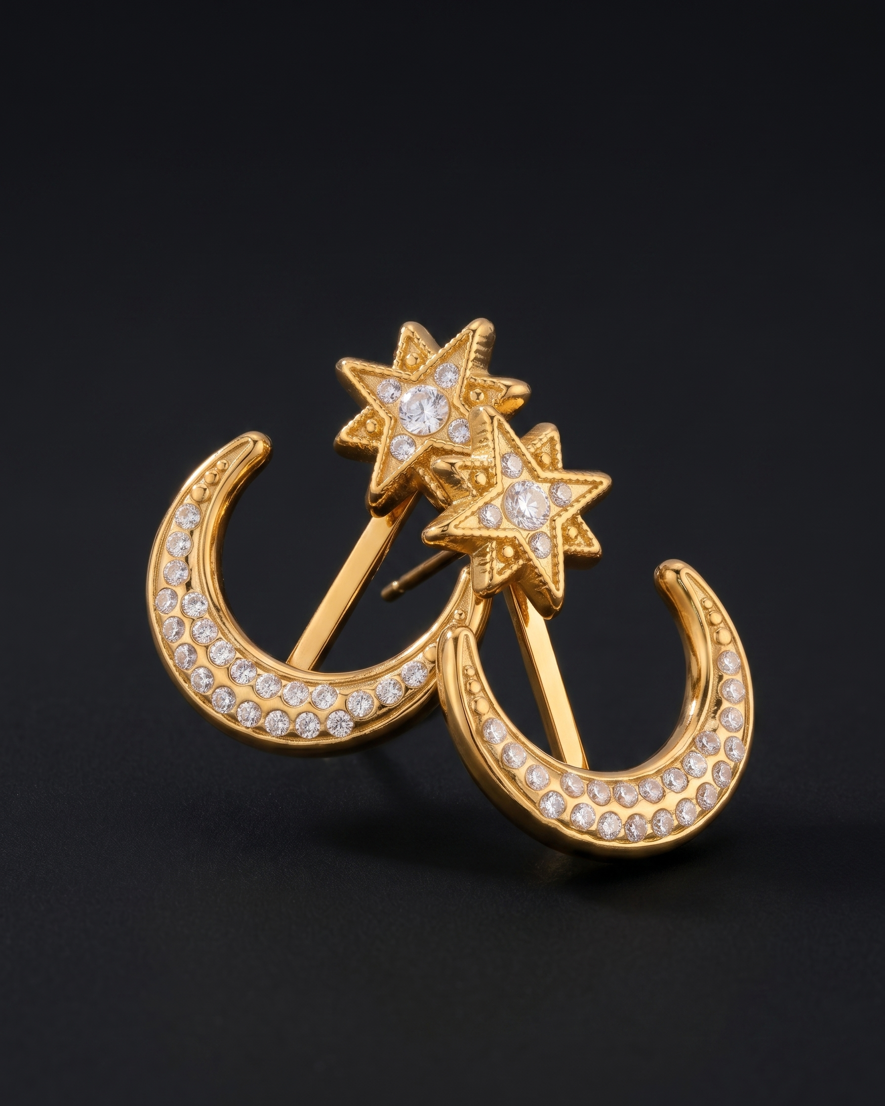 Gold earrings with star and crescent moon design on a black background