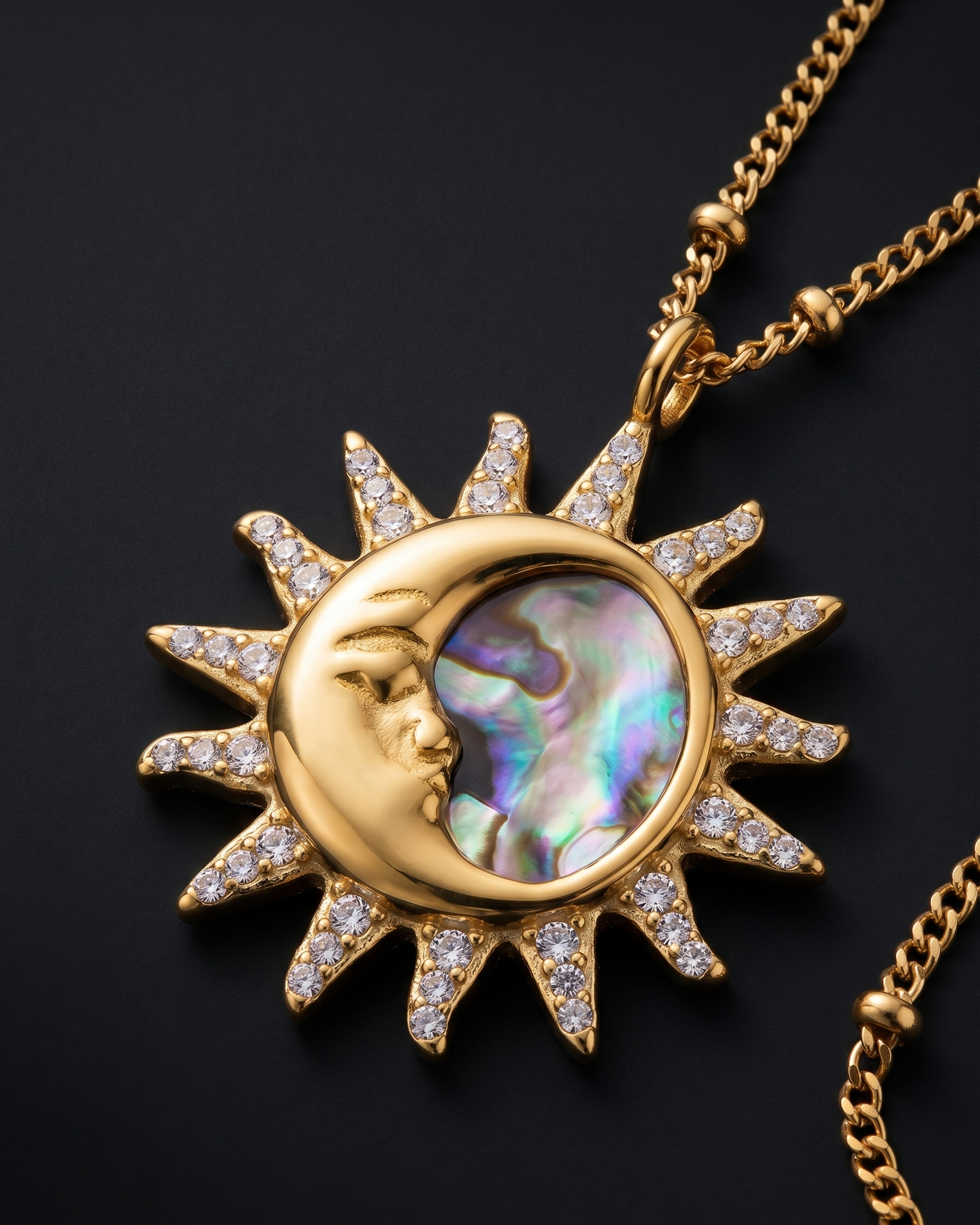 Gold necklace with a sun and moon pendant on a black background