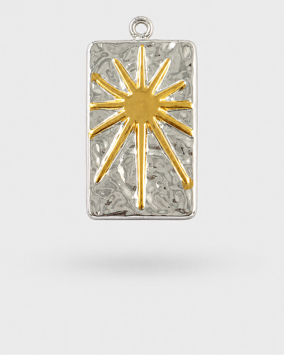 A rectangular silver pendant with a textured, hammered finish, featuring a raised gold sunburst design in the center and a small silver loop at the top for hanging.