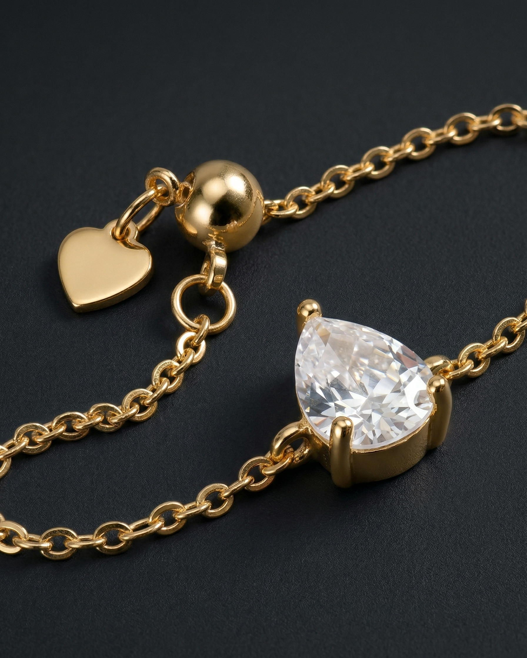 Gold necklace with a teardrop-shaped diamond pendant on a black background