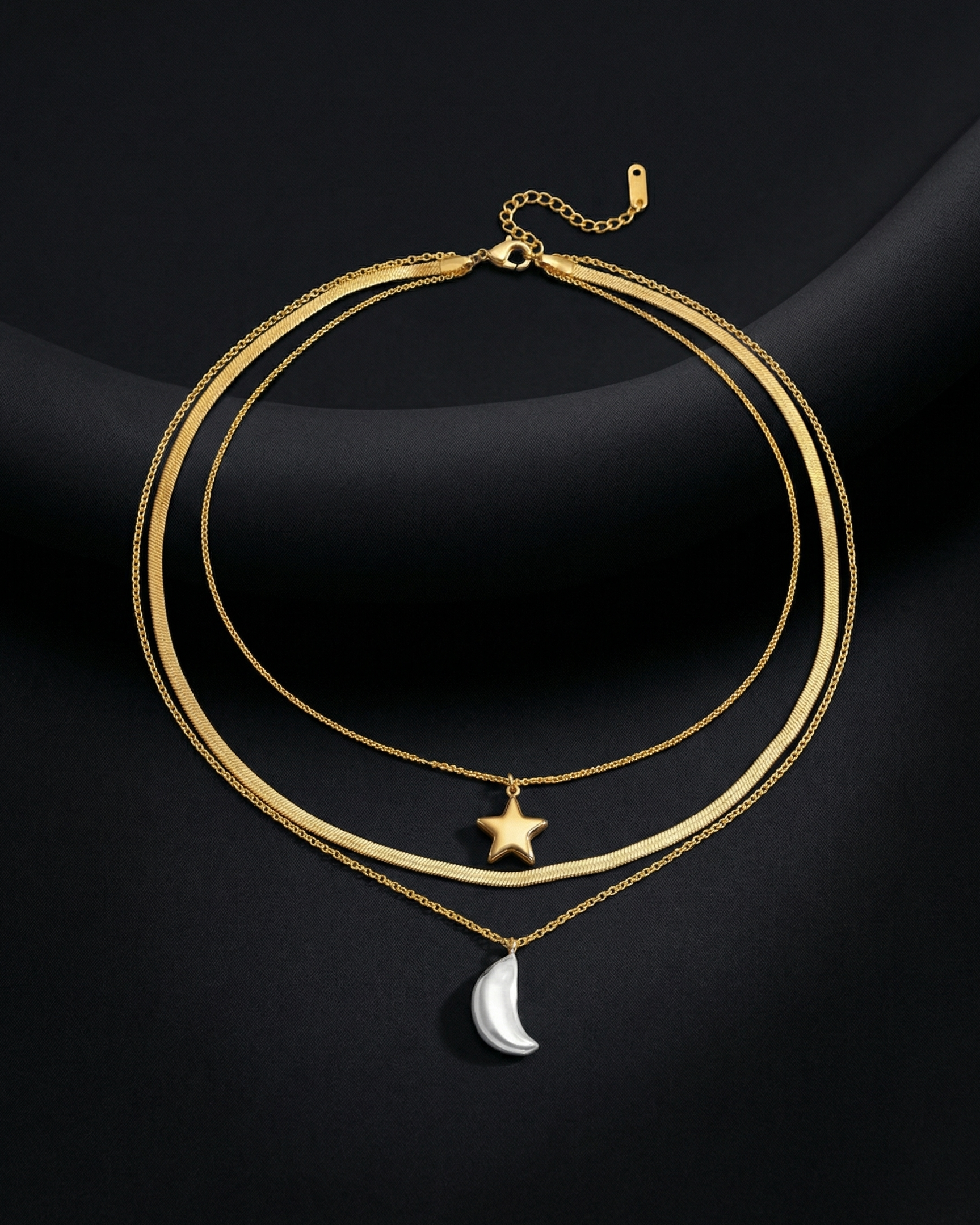 Gold necklace with star and moon pendants on a dark background