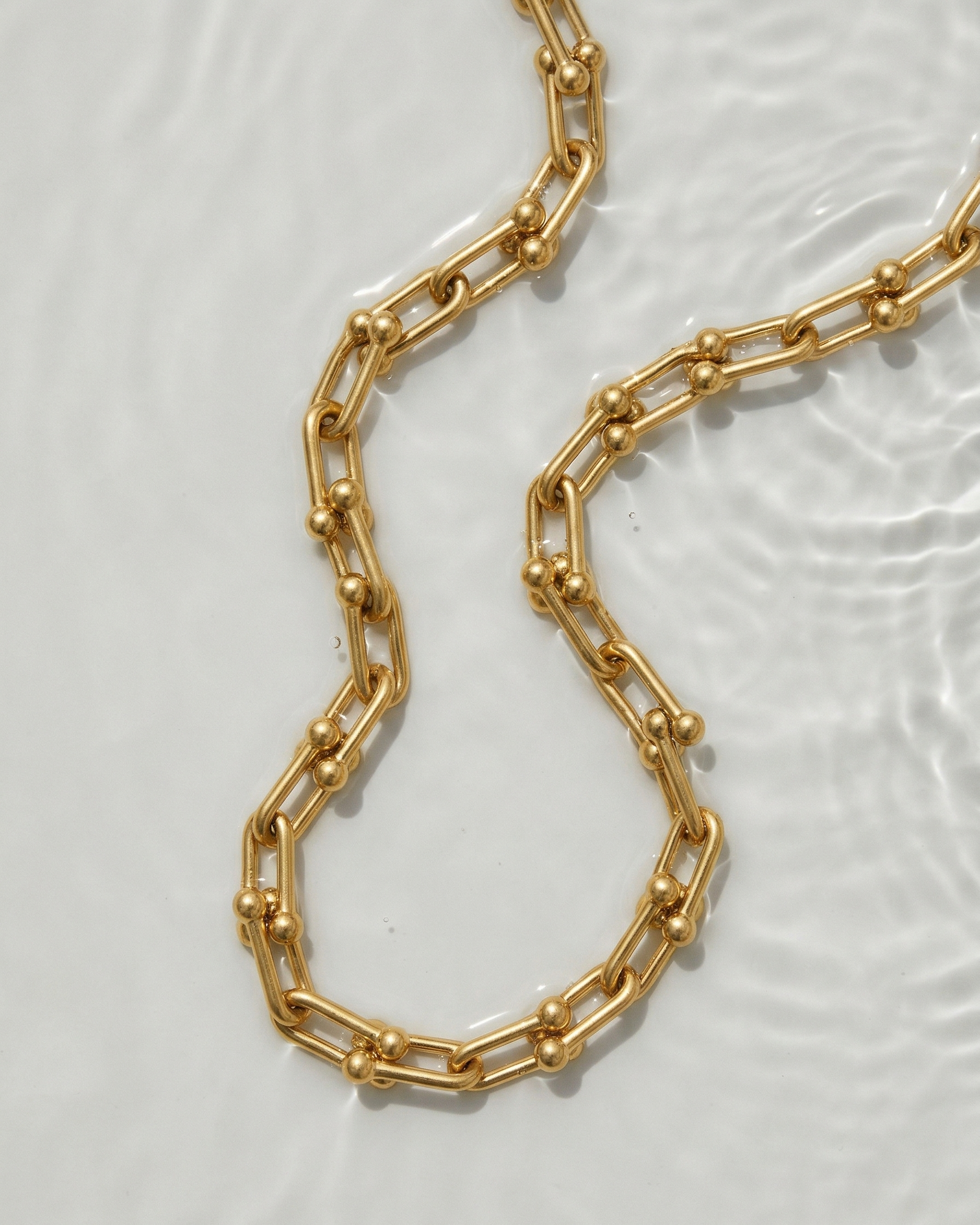 Gold chain necklace on a light gray background