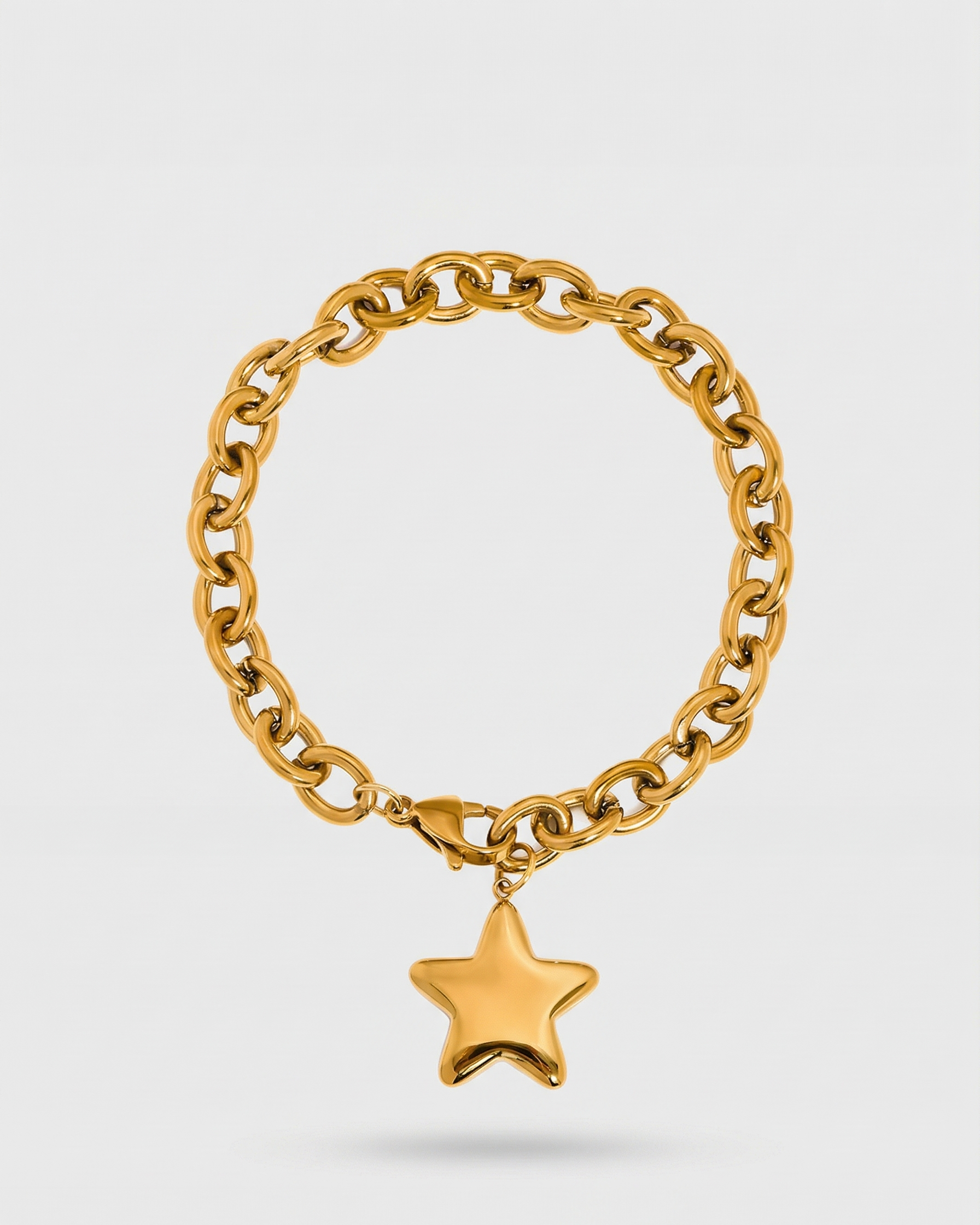 Gold chain bracelet with a star charm on a light gray background