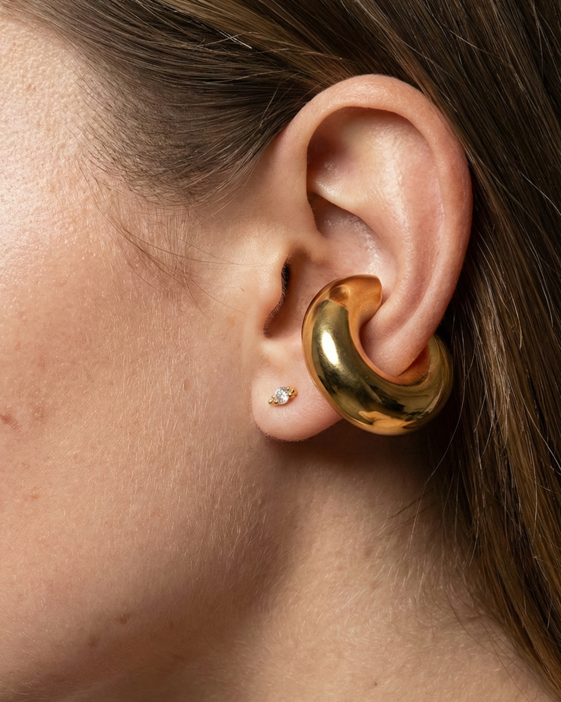 Close-up of a person wearing a gold hoop earring.