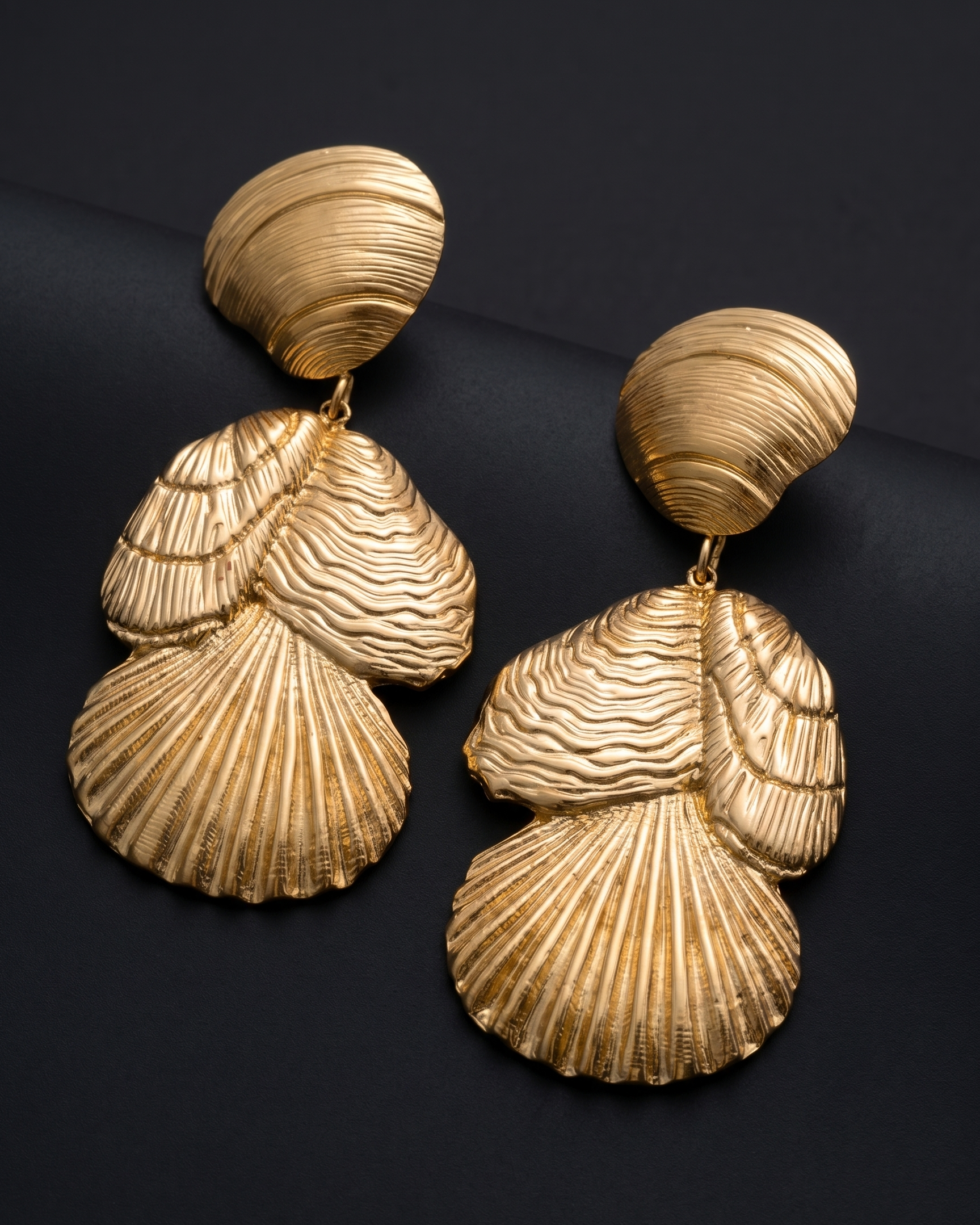 Gold shell-shaped earrings on a black background