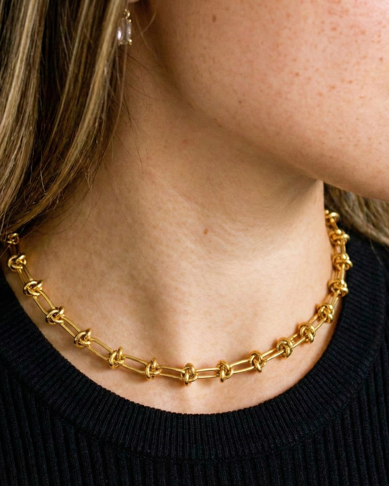 Gold chain necklace worn by a person with a black top