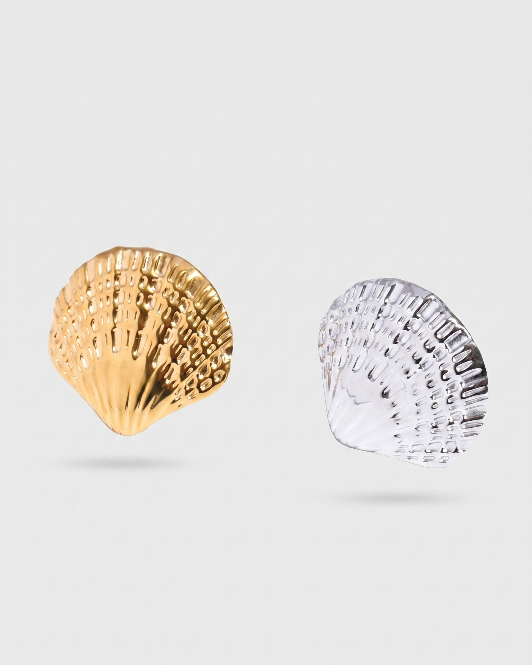 Gold and silver shell-shaped earrings on a light gray background