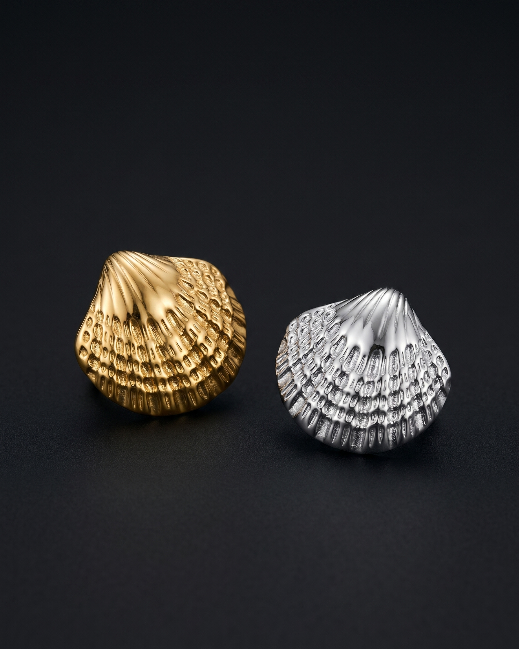 Gold and silver shell-shaped earrings on a black background