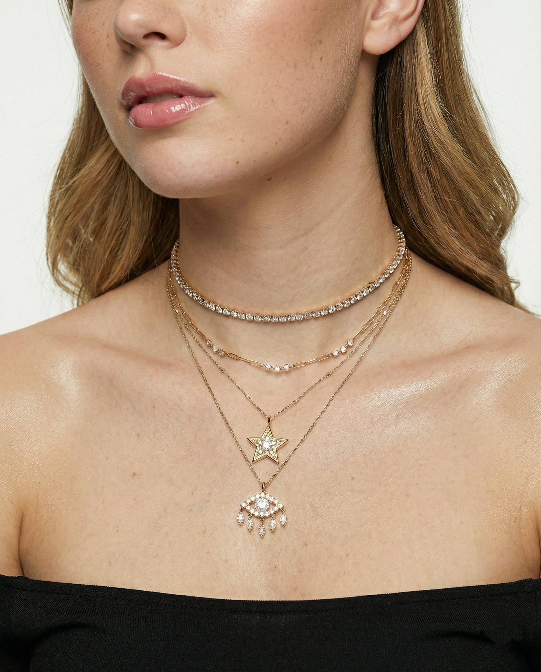 Close-up of a woman wearing multiple necklaces with star and heart pendants.