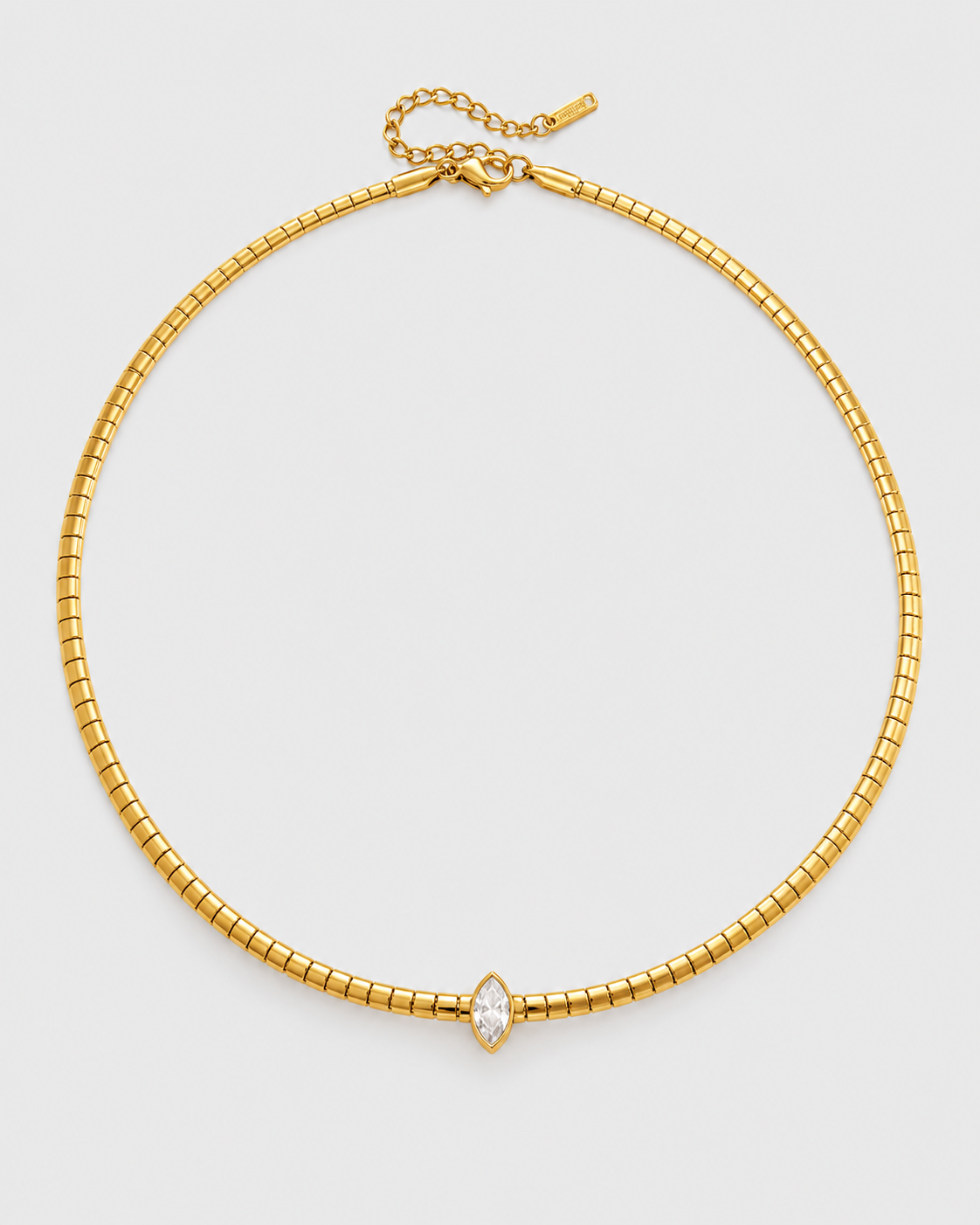 A gold snake chain choker necklace with a small marquise-cut clear gemstone at the center, displayed on a light gray background.