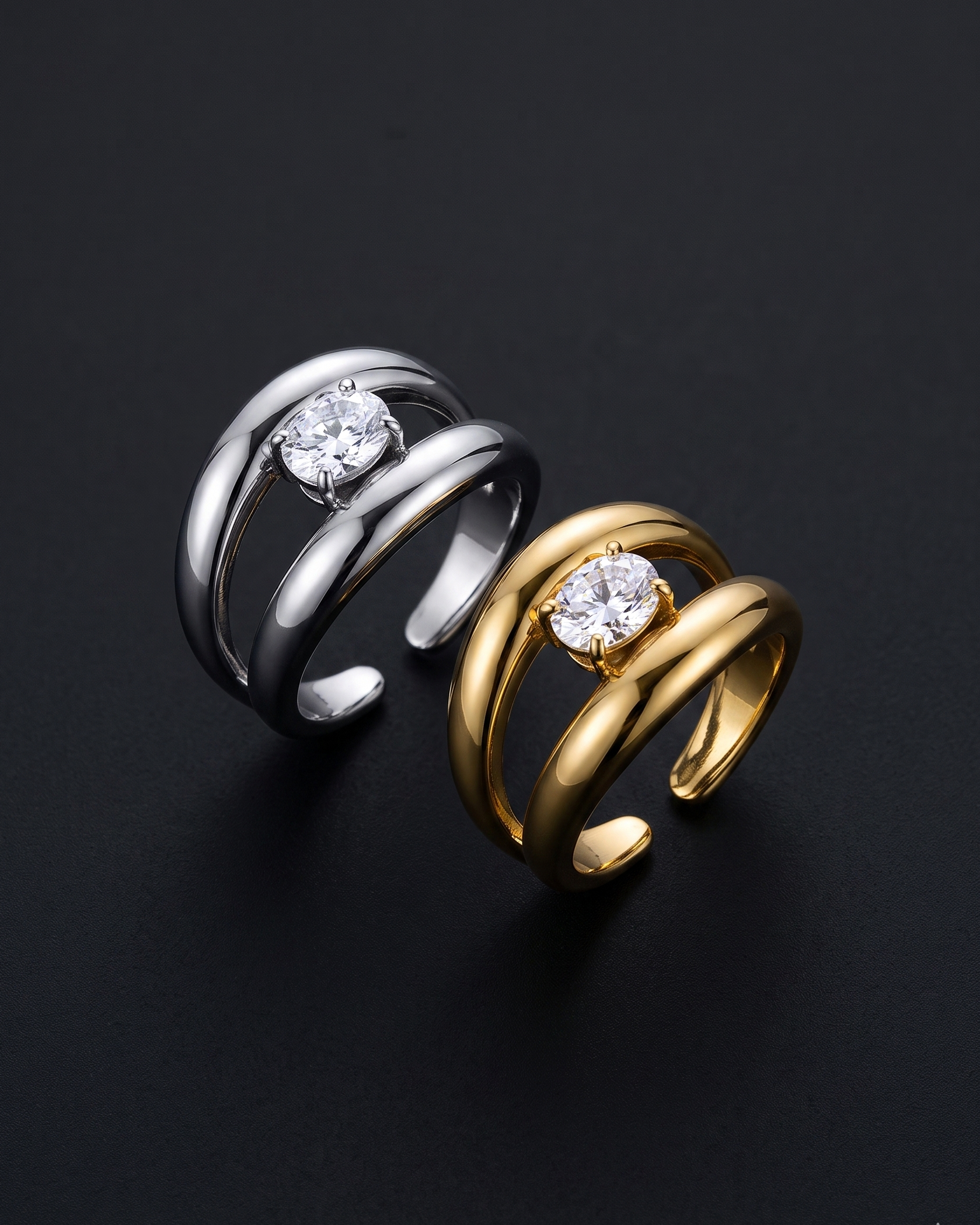 Two rings, one silver and one gold, with diamond-like stones on a dark background.