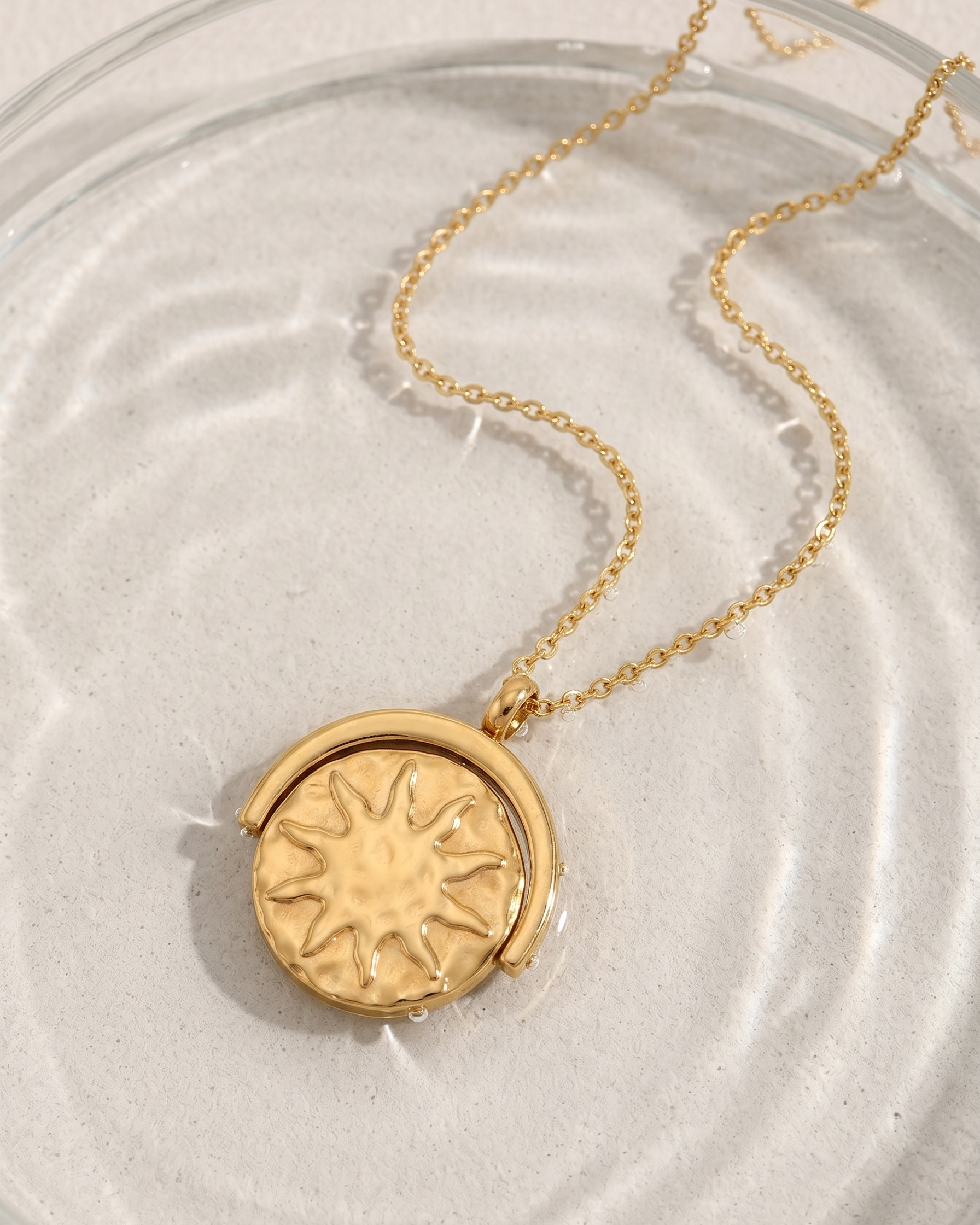 Gold necklace with a sun-shaped pendant on a light background