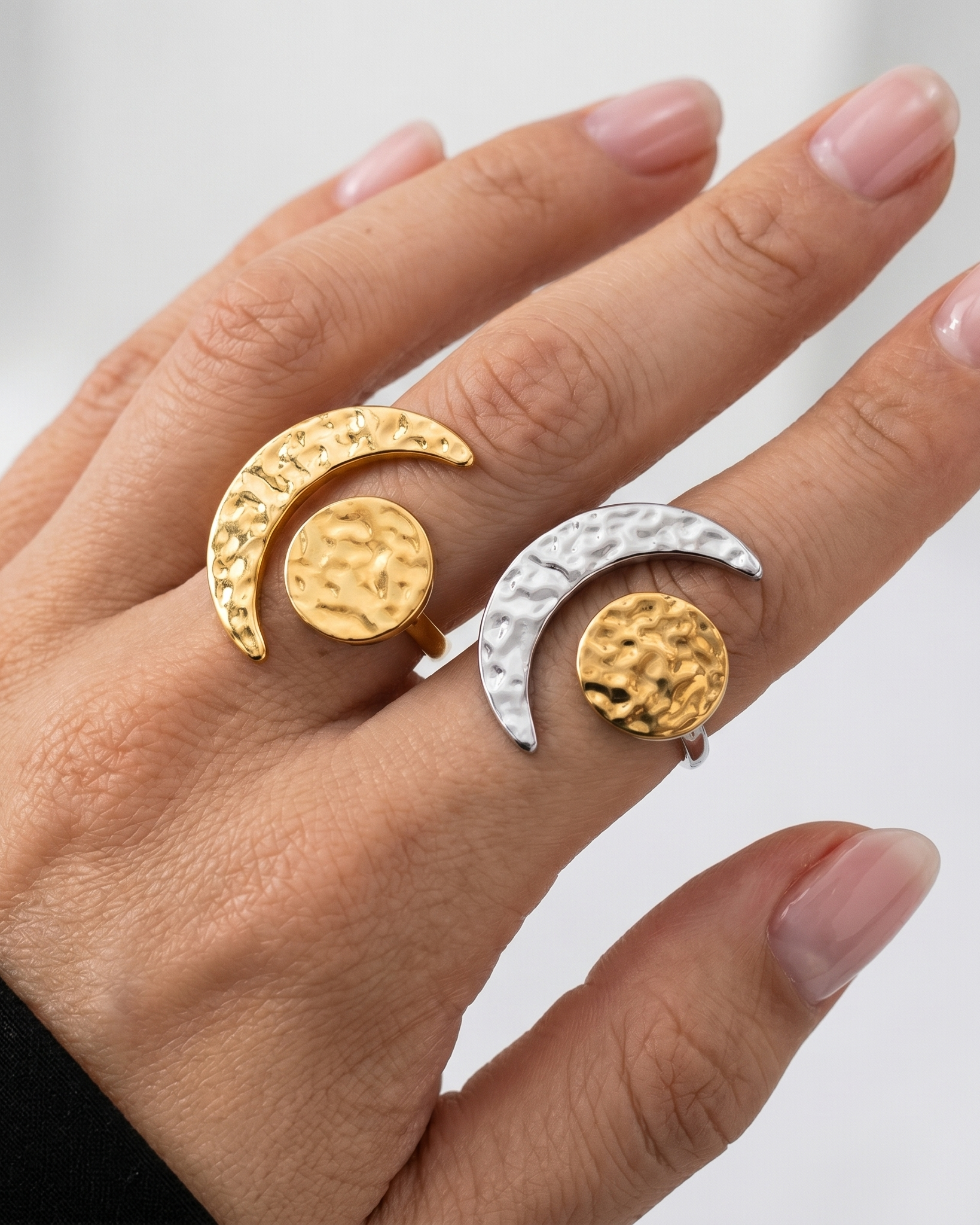 Hand wearing two gold and silver rings with a white background